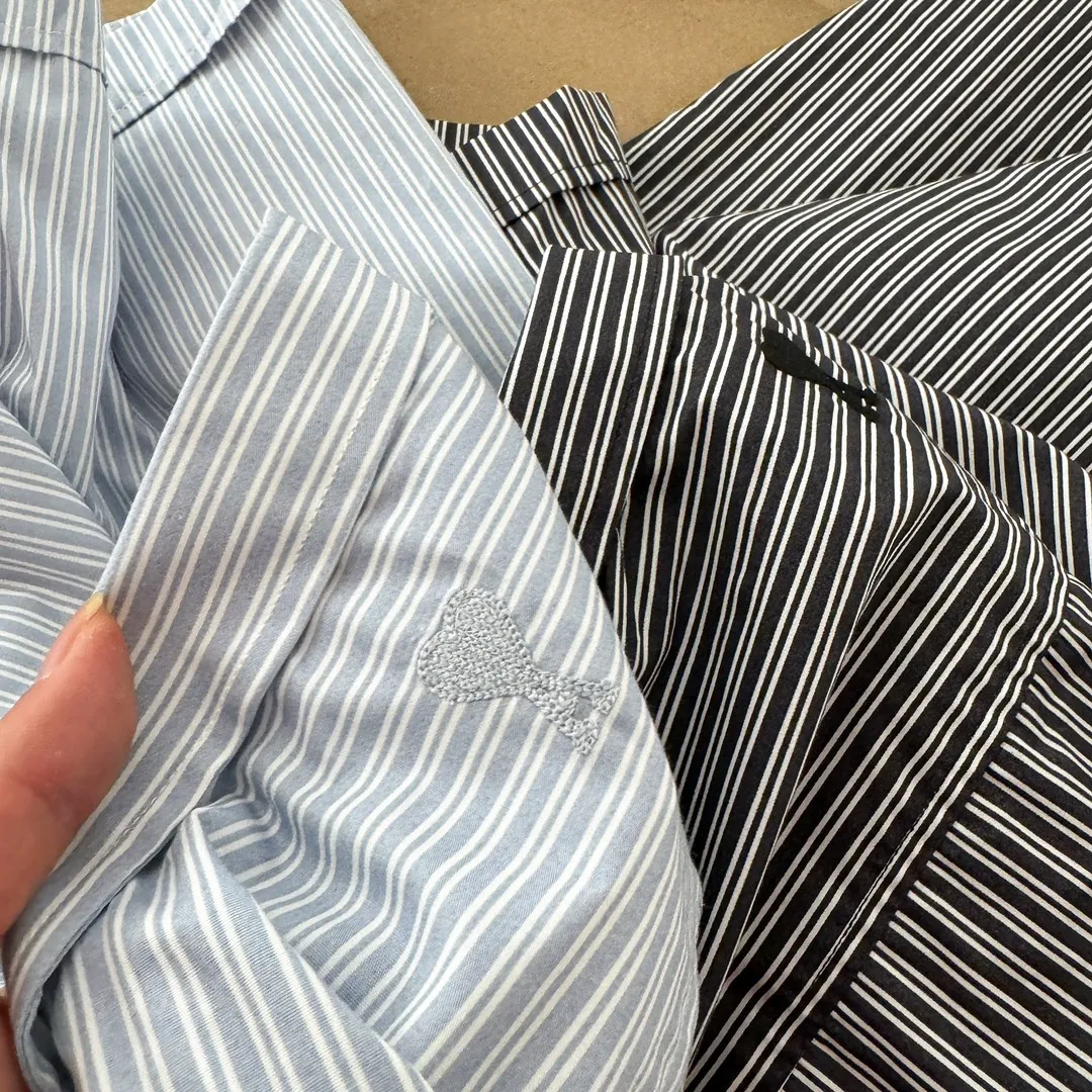 Ami Paris men's 24 spring and summer new love style loose cotton striped short shirt with the same color love at the back of the neck - the same style for men and women. The same color small love embroidery decoration at the back of the neck is fashionable and versatile long-sleeved shirt! On sale simultaneously at counters!  A well-known French affordable luxury fashion brand. The brand's classic elements are embellishments sought after by major celebrities. Its basic simple design and fashionable style make it a must-have couple's shirt for men and women!  Made of custom-woven 100% silk cotton material, it feels soft and delicate, has excellent moisture absorption and perspiration performance, and is very comfortable and skin-friendly when worn next to the skin! The simple and versatile pockets on the chest follow the consistent minimalist French attitude. The fabric is soft and comfortable, suitable for any versatile casual shirt couple!  Color: Blue Black Size: S-XL S: Bust 102, Shoulder 47, Length 70 M: Bust 106, Shoulder 48, Length 72 L: Bust 110, Shoulder 49, Length 74 XL: Bust 114, Shoulder 50, Length 76