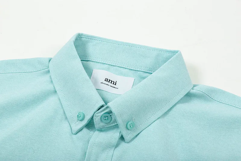 AMI Paris classic autumn heart embroidery in the same color on the chest. Casual cotton solid color short-sleeved Oxford shirt. Original custom-made 180g pure cotton fabric. Loose off-shoulder version. Same style for men and women. Color: Tianlan, white, green, pink, yellow, size: S-XL