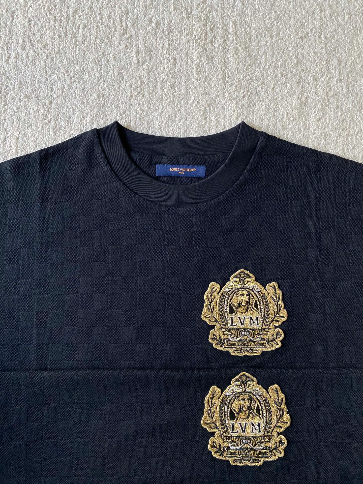 LV Golden Dog Chapter Round Neck Short Sleeve ⚠️Original purchase, 750; concealed jacquard fabric, standard version, full Damier jacquard pique, embellished with Dog Blason patch on the chest and embroidered handwritten Louis Vuitton logo # # on the back. Fully silk jacquard fabric, using 50S double-stranded silk, 210g; with 32S double yarn thread, 300g. The smooth jacquard fabric uses silk threads with better gloss as warp and weft threads, and uses complex jacquard technology to weave delicate and exquisite triangular patterns on the entire fabric. The fabric not only has a beautiful appearance and feel, but also has an overall higher quality feel. The silk jacquard fabric design adds a unique charm to the product through exquisite patterns and textures.  # The chest is embellished with Dog Blason patches and embroidered seals. The logo is made of imported custom-made embroidery thread. The glossy mercerized embroidery thread is dyed to give it a uniform and glossy finish. The exquisite embroidery machine combines complex embroidery needlework and fine detail processing to create a three-dimensional micro-relief embroidery effect.  Gold thread needle embroidery is a delicate and decorative embroidery technique. It is made of metal alloy threads with tight stitches, bright colors and high gloss. Wrap the gold wire around the spool, making sure the thread ends are neat and easy to manipulate to create a tight stitch.  # Imported embroidery thread plain embroidery technology. The handwritten embroidery is designed based on the original size and size to restore the overall three-dimensional visual effect. Using linen embroidery thread combined with encrypted processing, the embroidery body has a subtle matte visual texture; the embroidery effect is three-dimensional and full. The embroidery is very fine, the stitches are dense, the fonts are clear and the lines and three-dimensional feel are strong.  # Straight round neck version. Standard H hanging version, with shoulder-length design. The vertical version emphasizes that the width of the shoulders, waist, and hem are basically the same, and it is simple and loose. The short sleeves are tailored to fit the body of the wearer. At the same time, the neckline, cuffs and hem of the short sleeves are all designed with double lines.
