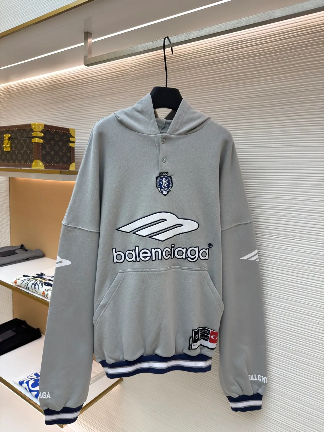 Balenciaga 3B football Polo hoodie ●Original version: purchased and developed by 10767 ●Item number: 1682334-B05 ●Fabric: cotton fabric ●Technology: embroidery applique production ●Color: gray ●Version: loose fit ●Weight: about 885 grams ●Size: XS-S-M-L ●Description: The neckline adopts a half-open button design and is decorated with metal badges to enhance the layered look; the main body of the garment presents the brand logo through three-dimensional foam printing technology, and the grayscale gradient effect enhances the visual texture. The cuffs and hem are edged with contrasting ribbing, which has moderate elasticity and is not easily deformed; a collage label is embedded in the left hem, and the details echo the brand's street style. The partial logo embroidery on the shoulders and cuffs echoes the main pattern. The overall craftsmanship takes into account practical wearability and brand recognition, making it suitable for daily casual or trendy looks. The overall wiring is straight and delicate, the fabric is comfortable and soft, and the color is consistent without color difference. It can be matched with the same style to create a fashionable look and control various occasions. Customized accessories, complete with three standards, same style for men and women!