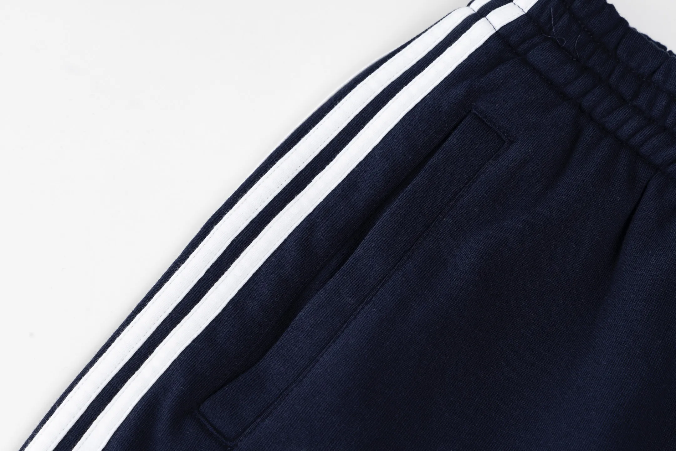 🅿️480 [Exclusive supply] BLCG circular embroidered webbing sweatpants. The fabric is made of single-sided fish scale fabric woven with cotton as the base. The front is a smooth knitted surface, and the skin-contacting surface is formed into three-dimensional terry through the floating thread knitting technology of the knitting machine, which increases the fluffiness and has a delicate touch. The terry structure absorbs a large amount of water and evaporates quickly, so it is not easy to loosen and deform after repeated washing. Using an imported embroidery machine with 3000 stitches, the front thigh is decorated with loop sports icon embroidery. The double-axis linear guide drives the embroidery frame, and the frame moving accuracy can reach 0.01mm/P, ensuring precise positioning of the embroidery pattern. The decorative strips are precisely positioned along the designated contours from the waist to the toes to ensure symmetry and overall smoothness. Before actual sewing, use very fine basting stitches for pre-fixing. This step is crucial to prevent the trim from slipping, twisting, or wrinkling during the sewing process and ensuring that the final stitch is straight and perfect. By actively interfering with the shrinkage potential of the cotton knitted surface, the fabric is able to transition from changeable to stable, improving dimensional stability while being less prone to deformation and wrinkles. Size:S/M/L/XL