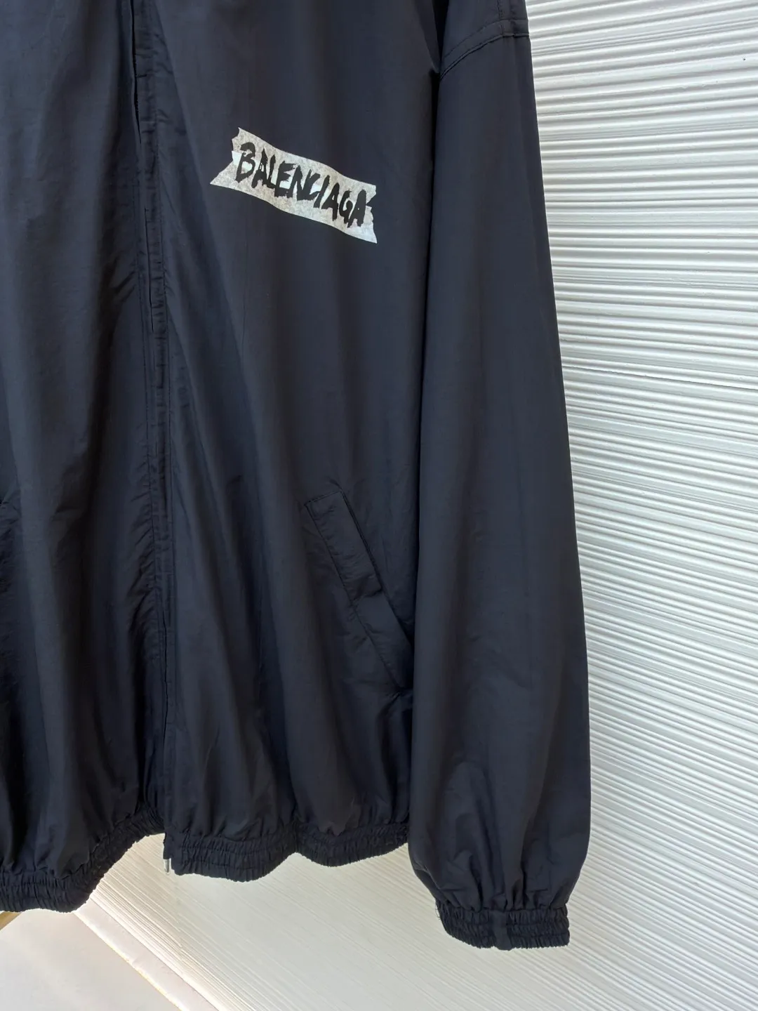Balenciaga glue print jacket ●Original version: Purchased and developed for 20000 ●Item number: 1682403-B40 ●Fabric: woven nylon fabric ●Technology: glue printing production ●Color: black ●Version: fitted version ●Weight: about 480 grams ●Size: XS-S-M ●Description: This Balenciaga cotton blended jacket is made of 65% cotton and 35% polyester fiber blended fabric. It is first processed by a high-temperature pre-shrinking process to control the fabric shrinkage within 1% to avoid deformation after wearing and washing. The brand logo on the front of the body is made using glue printing technology. Before printing, the fabric is statically eliminated, and then the glue is tightly combined with the fabric through 150℃ high temperature printing. The pattern is clear, does not fall off and is friction-resistant. The jacket adopts a stand-up collar zipper design. The metal zipper has been treated with anti-oxidation plating and is smooth and easy to pull. The cuffs and hem are made of elastic ribbing. The rib weaving method is 1*1 double-needle technology, which is durable and not easy to loosen. The side seam pockets use invisible inlay technology with a stitch density of 8 stitches per centimeter. The shoulders are seamlessly taped. The overall craftsmanship takes into account the brand's iconic simple design and durability, and the details highlight the production standards of high-end clothing. The overall wiring is straight and delicate, the fabric is comfortable and soft, and the color is consistent without color difference. It can be matched with the same style to create a fashionable look and control various occasions. Customized accessories, complete with three standards, same style for men and women!