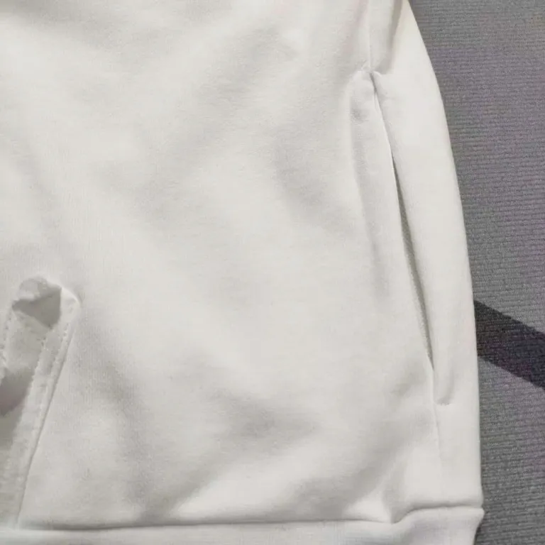 The top proven version of Balenciaga 23SS masking paper printed letters double-sided logo hooded loose hooded sweatshirt. This hoodie has a very interesting and cute design. The kangaroo pocket on the front of the large body is reverse-cut design. The double side pockets are hollow, which means that when viewed from the front, it actually deceives your vision. The real pockets are sewn on the reverse terry bottom. It is time-consuming and labor-intensive, but it is the core theme of the entire hoodie that cannot be ignored. The same detail is that the double side pockets are hemmed and stitched. And processed with holes; 480g heavy-weight pure cotton fabric with fine small terry bottom. After heavy mud dyeing and washing, the fabric still has a thick foundation and is comfortable and soft. The front and back double-sided textured paper transfer LOGO, and the front and back printing colors are different. The loose and large drop shoulder design is unisex. This style is also very suitable for girls to match. It is easy to create a lazy and casual street feel of the United States and France. Many holes are processed by hand grinding wheels on the body. Traces of muddying can be seen on the neckline, shoulder line, and side cuff splicing, but the visual effect transition is natural and soft without any sense of dirt. The old effect of the entire hoodie is excellent. The cuff threads are custom-woven in color; the packaging is washed and customized. The new gray silver letter main logo. The dropped shoulder model does not include shoulder width. The version is Kanye’s American style. Short and wide street casual version. From short sleeves to sweaters, this style is definitely not to be missed. Color: mud-dyed custom-woven navy Size: XS-S-M (Can be worn by both men and women, OS is loose and dropped on the shoulders) P:510