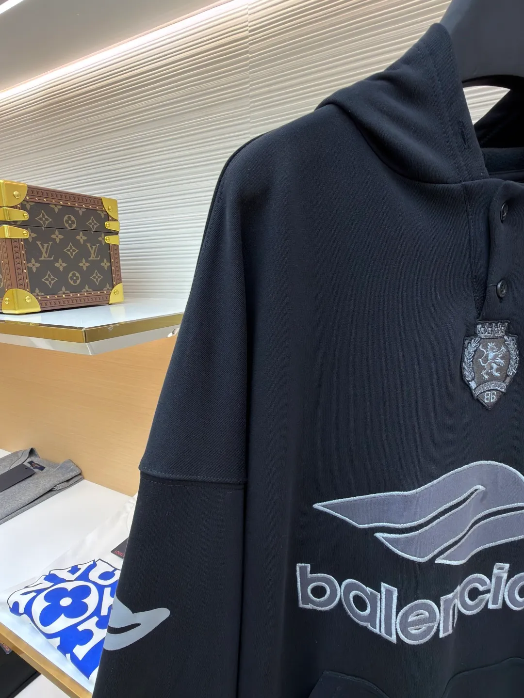 Balenciaga 3B football Polo hoodie ●Original version: Purchased and developed for 9999 ●Item number: 1681997-B40 ●Fabric: cotton fabric ●Technology: embroidery applique production ●Color: black ●Version: loose fit ●Weight: about 860 grams ●Size: XS-S-M-L ●Description: The neckline adopts a half-open button design and is decorated with metal badges to enhance the layered look; the main body of the garment presents the brand logo through three-dimensional foam printing technology, and the grayscale gradient effect enhances the visual texture. The cuffs and hem are edged with contrasting ribbing, which has moderate elasticity and is not easily deformed; a collage label is embedded in the left hem, and the details echo the brand's street style. The partial logo embroidery on the shoulders and cuffs echoes the main pattern. The overall craftsmanship takes into account practical wearability and brand recognition, making it suitable for daily casual or trendy looks. The overall wiring is straight and delicate, the fabric is comfortable and soft, and the color is consistent without color difference. It can be matched with the same style to create a fashionable look and control various occasions. Customized accessories, complete with three standards, same style for men and women!