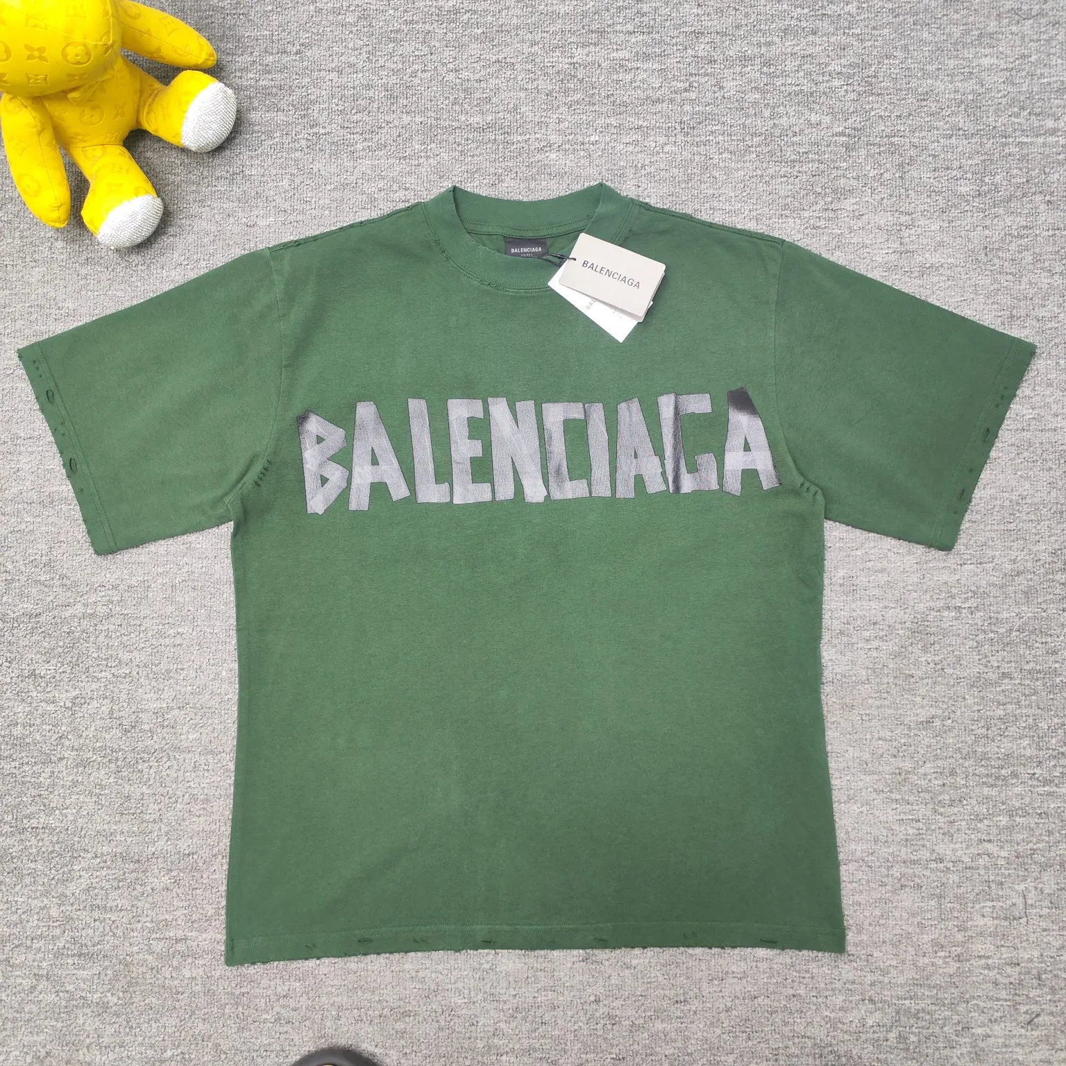 [Breaking new arrival] Top quality BALENCIAGA Paris spring and summer latest tape print washed and worn male and female couple star same style short sleeves 23ss tape tye black retro plain fabric medium version short sleeves Paris' new season's products have added the elements of artistic tape stickers, hot rhinestones and post-it notes, changing the previous minimalist printing style, this time the creativity is really laborious. The micro-OS style is friendly to both men and women. The fixed yarn and washed cotton are soft and waxy and resistant to damage. The slightly distressed worn details are a no-brainer for me who likes 𝐕𝐢𝐧𝐭𝐚𝐠𝐞. There are two styles of front and back printing. The front is like paper tape, and the back is a bright yellow graffiti painting effect, which has a strong impact on people. It looks great with denim overalls, and it’s super cool for girls to wear it with their lower body missing. Original custom-woven and dyed pure cotton material, heavily distressed. Counter 1/1; This product has a unisex design. The same oversize version for men and women·Tape Type logo on the front and back. It is characterized by heavy wear and washable effect. Color: dark green P; 140 Size: XS-L
