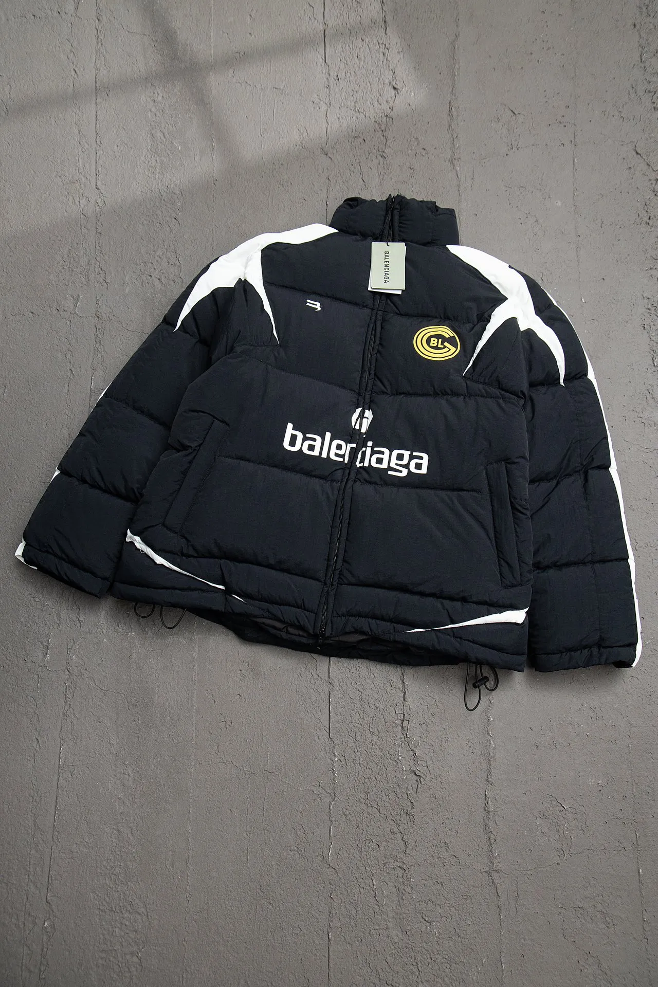 💰760 [Highest version, differentiated currency] Balenciaga / Balenciaga Blcg 24SS Manchester United football No. 10 black and white stitching joint stitching training down jacket, official website synchronized. The surface fabric and lining are made of customized high-density cloud-feel nylon fabric. The fabric has a level 4 water-repellent coating process. The lining is made of double-layer 330 gallbladder. Filled with 600 grams of Xinjiang pearl particle cotton. Extremely full!  The fabrics are the same as the original. Double-layer materials are used. The whole dress is full of style. Professional pattern makers from the original big-name OEM factory make patterns. Laser three-dimensional cutting. Because there are many splicing places, ordinary pattern makers are difficult to handle. Good products are made with care. Good goods take a long time. The whole body embroidery is operated by professional embroidery machines imported from island countries to make the embroidery details reach the top level. The whole body printing parts are operated using imported environmentally friendly offset printing technology. The printing is firm. The whole clothing accessories are molded and customized with hardware zippers and air holes. Double-hole limit buckle All have the same LOGO as the original version. Customized and washed as the original version. Main mark. Brand zipper seal bag. Brand LOGO moisture-proof paper. 3D laser cutting. Double-layer material. 5 meters of cloth for the whole piece. Extremely high cost. Composed of 47 pieces. Very slow production. Zipper pockets on both sides. Elastic cuff design. Imported environmentally friendly glue thermoset ink printing technology. Tajima high-speed embroidery machine embroidery Sporty B. Three-dimensional and full. The cuffs are equipped with new custom football embroidery patches. Customized hardware zippers. Double slider design. Customized original air holes. Customized original logo double-hole limit buckles. Original main mark and washed tag. Brand packaging. Color: black. Size: 46/48/50/52.