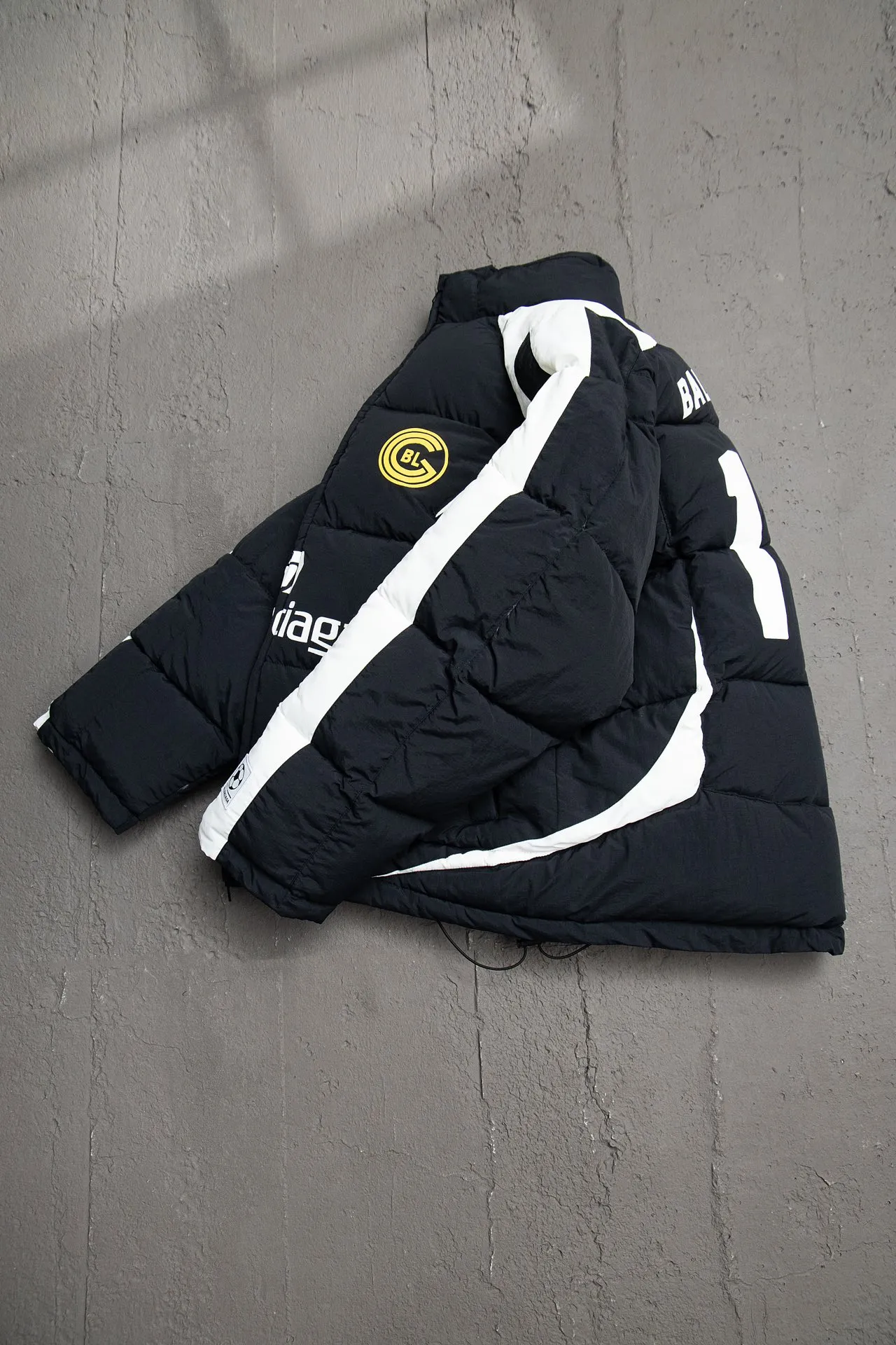 💰760 [Highest version, differentiated currency] Balenciaga / Balenciaga Blcg 24SS Manchester United football No. 10 black and white stitching joint stitching training down jacket, official website synchronized. The surface fabric and lining are made of customized high-density cloud-feel nylon fabric. The fabric has a level 4 water-repellent coating process. The lining is made of double-layer 330 gallbladder. Filled with 600 grams of Xinjiang pearl particle cotton. Extremely full!  The fabrics are the same as the original. Double-layer materials are used. The whole dress is full of style. Professional pattern makers from the original big-name OEM factory make patterns. Laser three-dimensional cutting. Because there are many splicing places, ordinary pattern makers are difficult to handle. Good products are made with care. Good goods take a long time. The whole body embroidery is operated by professional embroidery machines imported from island countries to make the embroidery details reach the top level. The whole body printing parts are operated using imported environmentally friendly offset printing technology. The printing is firm. The whole clothing accessories are molded and customized with hardware zippers and air holes. Double-hole limit buckle All have the same LOGO as the original version. Customized and washed as the original version. Main mark. Brand zipper seal bag. Brand LOGO moisture-proof paper. 3D laser cutting. Double-layer material. 5 meters of cloth for the whole piece. Extremely high cost. Composed of 47 pieces. Very slow production. Zipper pockets on both sides. Elastic cuff design. Imported environmentally friendly glue thermoset ink printing technology. Tajima high-speed embroidery machine embroidery Sporty B. Three-dimensional and full. The cuffs are equipped with new custom football embroidery patches. Customized hardware zippers. Double slider design. Customized original air holes. Customized original logo double-hole limit buckles. Original main mark and washed tag. Brand packaging. Color: black. Size: 46/48/50/52.