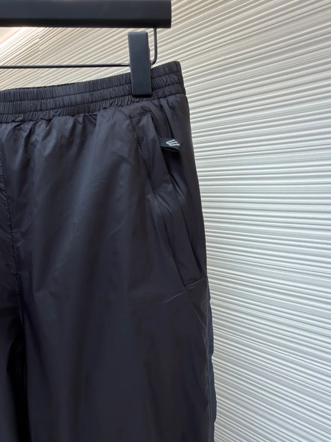 Balenciaga SKIWEAR series 3B printed fleece ski pants ●Original version: purchased and developed by 12414 ●Item number: 1682492-B25 ●Fabric: nylon fabric ●Technology: printing production ●Color: black ●Version: fitted version ●Weight: about 415 grams ●Size: S-M-L-XL ●Description: High-density technological nylon fiber is selected, and a delicate matte texture is created through a special textile process. The black tone presents a low-key and high-end visual effect. The fabric is lightweight yet stiff, has excellent wrinkle resistance and abrasion resistance, and is not prone to pilling or deformation for daily wear. It also has certain windproof properties to cope with changeable weather. The inner lining is made of high-density fluff material with excellent fluffiness and elasticity. When it closely fits the skin, it can form a layer of warm air, effectively locking in heat and improving the warmth factor of winter wear. The down fiber is delicate and smooth, avoiding the rough feeling of traditional plush fabrics, achieving the dual experience of "lightness and no burden" and "constant temperature and warmth", taking into account both comfort and practicality. Imported silicone printing technology is used on both sides of the trouser legs to present the iconic 3B sports icon pattern in a relief-like three-dimensional form. The silicone material has been pressed at high temperature and is tightly integrated with the fabric, making it difficult to fall off and crack. At the same time, it retains a delicate matte luster, forming a subtle texture contrast with the pants fabric, highlighting the brand recognition in a low-key manner. The mid-waist design is equipped with a double-layer elastic rib waistband and a built-in adjustable drawstring. The elastic fiber at the waistband has been pre-shrunk to ensure that it is not easy to loosen after long-term wear. It can not only stabilize the waist shape, but also adapt to the activity needs of different body shapes, taking into account sports functionality and daily comfort. The overall wiring is straight and delicate, the fabric is comfortable and soft, and the color is consistent without color difference. It can be matched with the same style to create a fashionable look and control various occasions. Customized accessories, complete with three standards, same style for men and women!