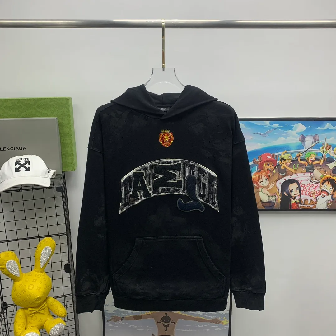 Top tested version 23FW BALENCIAGA Paris Manchester United limited edition distressed male and female couple star same style pure cotton loose hooded sweatshirt [very suitable for Douyin, and other platforms! The letters in the LOGO position have been damaged and polished! 】 The fabric is custom-made washed knitted cotton terry material. The upper body is very soft. The front panel uses a classic hand pocket with a worn effect. The overall yellow and dirty effect is all artificially sprayed with majolica. It requires proficiency and experience to achieve this natural and elegant effect!  Customized towel embroidery on the chest, heavily damaged! The aging effect is very obvious! The overall artificial positioning coating is hand-made, washed and dirty. The frayed hole craftsmanship has a hand-painted graffiti effect. The arms behind the bend are made of open-stitch frayed craftsmanship. The wiring is delicate. Elastic cuff design. The whole body is hand-positioned with muddy dyeing and frayed effect! Ready-made garments are washed twice with water +➕ once with wax. It feels smooth!   The Manchester United letters and logo on the chest are designed with full embroidery and the details are visible!  Size: XS-L Color: White Black P: 470