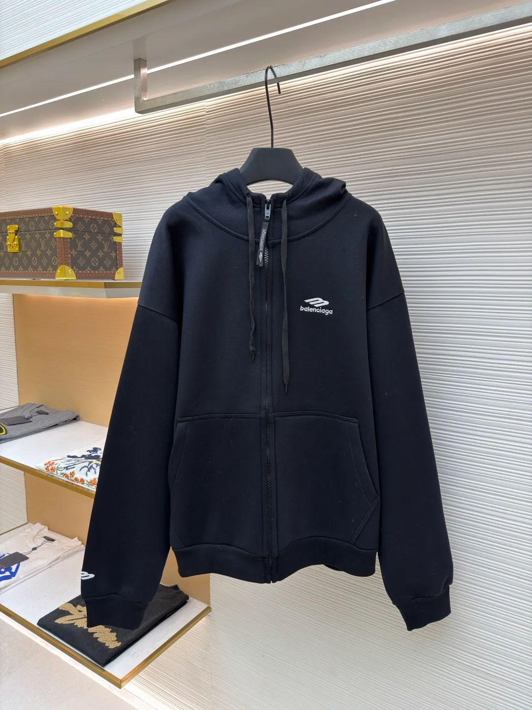 Balenciaga SIK WEAR ski series velvet hooded sweatshirt ●Original version: purchased and developed for 9999 ●Item number: 1681932-B15 ●Fabric: velvet fabric ●Technology: embroidery production ●Color: black ●Version: loose fit ●Weight: about 945 grams ●Size: XS-S-M-L ●Description: It adopts a high-count and high-density plain knitting structure. The surface shows an extremely delicate and smooth texture, giving the garment a low-key and high-end matte texture. This is in sharp contrast to traditional heavy and fluffy ski suits, achieving a balance between "light weight" and "excellent performance." After being treated with Teflon coating, the surface of the fabric can resist being soaked by snow water, while maintaining a certain degree of breathability to avoid accumulation of sweat inside. The fabric may also be tear-resistant and have some elasticity to ensure freedom of movement and durability during skiing. The interior is made of velvet material. By creating a large number of tiny air traps on its surface, a layer of still air is formed, which effectively locks body heat and achieves excellent warmth retention. The materials selected focus on skin-friendly feeling to avoid the itching that may be caused by ordinary thermal insulation materials. At the same time, excellent fleece has quick-drying properties, which can quickly export internal moisture to the outer layer for evaporation, keeping the skin dry and comfortable. It is perfect for the micro-environment of alternating hot and cold conditions when skiing. Zippers are not commercially available, but "customized rubber zippers" specially developed for the SIKWEAR series. Its teeth are treated with high-performance polymer or rubber to ensure they are smooth and durable in extremely cold environments and are not easy to freeze. The design of the zipper puller must also be ergonomically considered to facilitate operation when wearing gloves. Customized jacquard webbing, jacquard weaving technology can create clear, three-dimensional and never fall off patterns, its texture and firmness are far better than ordinary printing. This webbing becomes the main visual axis that runs through the front of the garment, making it highly recognizable. The letters are finished with Tajima embroidery. The effect is far superior to ordinary computer embroidery. It is characterized by extremely dense and even stitches, clear and sharp edges, and full and three-dimensional patterns. The direction and tension of each stitch are precisely controlled to ensure that the logo remains in perfect shape under any wearing condition and will not wrinkle or deform. The rich texture and luster brought about by this craftsmanship are core expressions of luxury identity. SIKWEAR velvet hooded sweatshirt is a piece of clothing art that integrates cutting-edge technological fabrics, sophisticated functional design, luxurious custom details and palace-level craftsmanship. It breaks the boundaries between professional ski wear and everyday fashion, creating a complete narrative about modern luxury sportswear. It's more than just a sweatshirt for keeping warm, it's a piece of equipment for connoisseurs who pursue ultimate performance and top-notch fashion. The overall wiring is straight and delicate, the fabric is comfortable and soft, and the color is consistent without color difference. It can be matched with the same style to create a fashionable look and control various occasions. Customized accessories, complete with three standards, same style for men and women!