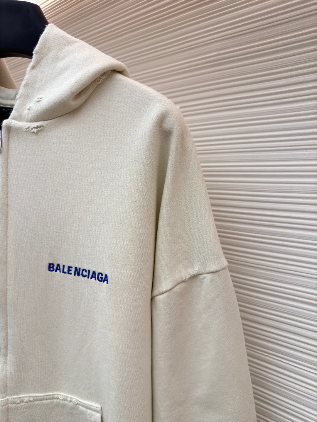 Balenciaga letter embroidered hooded zipper long-sleeved sweatshirt ●Original version: Purchased and developed for 9200 ●Item number: 1682263-A95 ●Fabric: combed cotton ●Technology: Washed and frayed ●Color: white ●Version: loose fit ●Weight: about 965 grams ●Size: S-M-L ●Description: This Balenciaga letter embroidered hooded zipper sweatshirt is made of 380g heavyweight pure cotton terry cloth, which has been treated with enzyme washing process. The fabric has a natural old-fashioned soft and waxy texture. At the same time, the stone grinding process is used to create irregular raw edge effects on the cuffs and hem, restoring the retro street style. The body adopts a loose, dropped-shoulder version, and the three-dimensional tailoring makes the shoulder lines smooth. The hooded part has a built-in drawstring made of pure cotton and is pre-shrunk to prevent it from deforming. The custom-made metal zipper on the front zipper closes smoothly and has no lag after repeated opening and closing tests. The brand letters on the left chest are made with imported embroidery machines using flat embroidery stitches, using polyester thread with high color fastness. The stitches are fine and neat without skipping, and the letter outline is three-dimensional and clear. The overall stitching uses double-needle overlocking technology, with up to 12 stitches per inch. The ribbed edges on the cuffs and hem are made of spandex blended material, which has long-lasting elasticity and is not easy to loosen, taking into account both wearing comfort and stiffness. The overall wiring is straight and delicate, the fabric is comfortable and soft, and the color is consistent without color difference. It can be matched with the same style to create a fashionable look and control various occasions. Customized accessories, complete with three standards, same style for men and women!