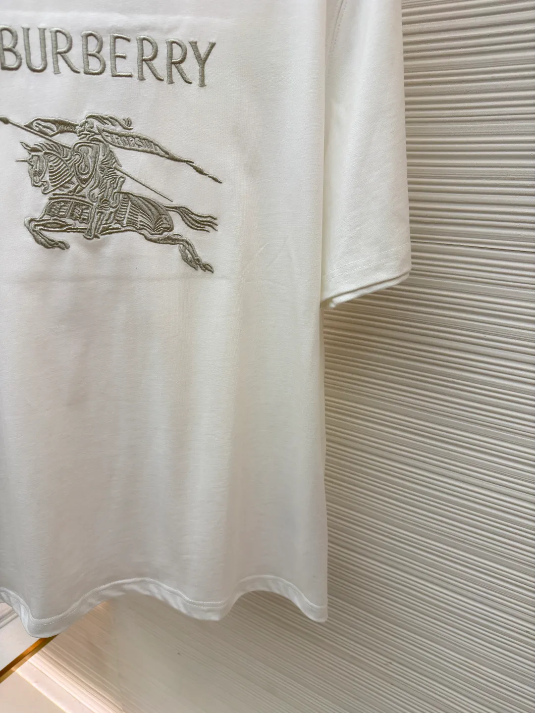 Burberry Thin Line War Horse Embroidery Round Neck Short Sleeve ●Original version: 3250 purchase and development ●Item number: 1681453-X90 ●Fabric: pure cotton fabric ●Technology: embroidery production ●Color: white ●Version: fitted version ●Weight: about 300 grams ●Size: S-M-L-XL ●Description: This T-shirt is made of high-quality pure cotton fabric, which is skin-friendly and breathable. Black and off-white tones are classic and versatile. The brand knight logo on the front adopts precision embroidery technology. The silk thread is rich in color, the stitching is delicate and three-dimensional, and the pattern is rich in layers, highlighting the high brand recognition. The round neck structure is processed by overlocking technology, and the neckline fits the neck and is not easily deformed. The body of the garment is sewn using industrial-grade flat stitching technology. The stitches are smooth and even, and the stitches at the hem and cuffs are fine and firm. From the selection of pure cotton fabrics to the control of embroidery details, every process reflects Burberry's pursuit of craft precision and classic style. It not only retains the daily practicality of the T-shirt, but also demonstrates the brand's light luxury recognition through exquisite embroidery. It is a fusion of casual style and exquisite craftsmanship. The overall wiring is straight and delicate, the fabric is comfortable and soft, and the color is consistent without color difference. It can be matched with the same style to create a fashionable look and control various occasions. Customized accessories, complete with three standards, same style for men and women!