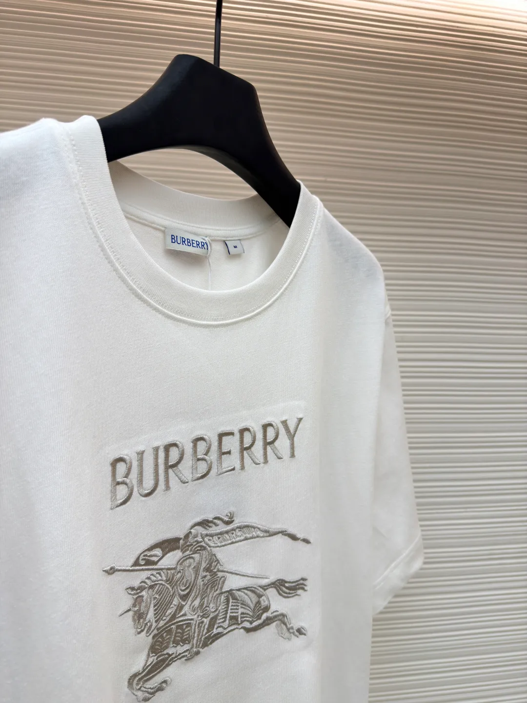 Burberry Thin Line War Horse Embroidery Round Neck Short Sleeve ●Original version: Purchased and developed for 3250 ●Item number: 1681453-X85 ●Fabric: pure cotton fabric ●Technology: embroidery production ●Color: black ●Version: fitted version ●Weight: about 275 grams ●Size: S-M-L-XL ●Description: This T-shirt is made of high-quality pure cotton fabric, which is skin-friendly and breathable. The black and off-white tones are classic and versatile. The brand knight logo on the front adopts precision embroidery technology. The silk thread is rich in color, the stitching is delicate and three-dimensional, and the pattern is rich in layers, highlighting the high brand recognition. The round neck structure is processed by overlocking technology, and the neckline fits the neck and is not easily deformed. The body of the garment is sewn using industrial-grade flat stitching technology. The stitches are smooth and even, and the stitches at the hem and cuffs are fine and firm. From the selection of pure cotton fabrics to the control of embroidery details, every process reflects Burberry's pursuit of craft precision and classic style. It not only retains the daily practicality of the T-shirt, but also demonstrates the brand's light luxury recognition through exquisite embroidery. It is a fusion of casual style and exquisite craftsmanship. The overall wiring is straight and delicate, the fabric is comfortable and soft, and the color is consistent without color difference. It can be matched with the same style to create a fashionable look and control various occasions. Customized accessories, complete with three standards, same style for men and women!
