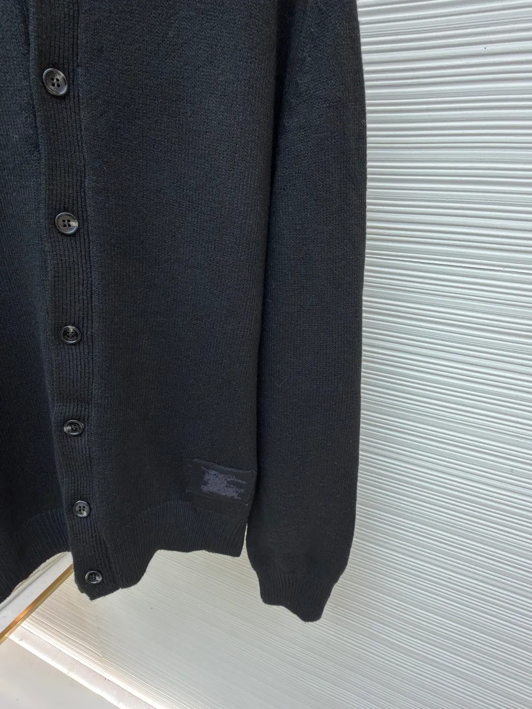 Burberry lapel rib knitted cashmere sweater ●Original version: purchased and developed by 11575 ●Item number: 1682226-B15 ●Fabric: wool blended fabric ●Technology: knitted ●Color: black ●Version: fitted version ●Weight: about 600 grams ●Size: S-M-L-XL ●Description: This black knitted cardigan is knitted with high-count worsted wool yarn. The main body is built using four-flat stitch technology, which gives the fabric good elasticity and shapeability, while forming a fine and tight texture. The ribbed lapel weaving process is used at the neckline, and a combination of different needle types is used to create a crisp collar profile. The rib structure can be freely expanded and contracted according to the wearing status to fit the neck line. The placket adopts inlaid buttonhole technology and is matched with matte resin buttons of the same color. The buttons and the body are fixed by hand-stitching, which is strong and beautiful. The brand logo patch on the lower side of the body is processed by a hot-pressing bonding process and fits seamlessly with the knitted fabric. The overall cut is a slightly loose shoulder-drop version, combined with three-dimensional darting technology, which ensures wearing comfort while creating clean lines. Every knitting node is manually inspected to ensure the uniformity and integrity of the knitted texture. The overall wiring is straight and delicate, the fabric is comfortable and soft, and the color is consistent without color difference. It can be matched with the same style to create a fashionable look and control various occasions. Customized accessories, complete with three standards, same style for men and women!
