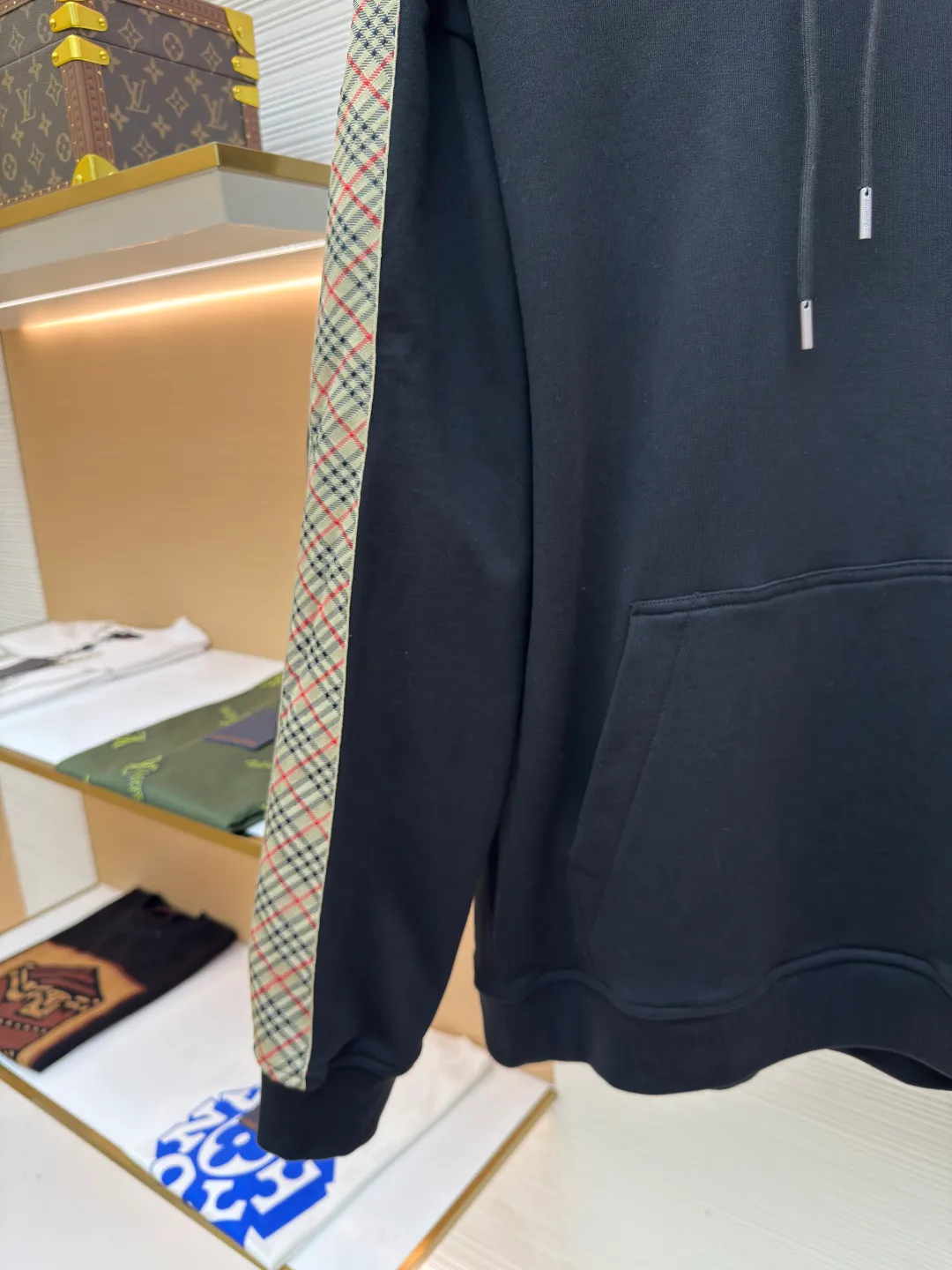 BURBERRY Ribbon trim hooded pullover sweatshirt ●Authentic product: Purchased and developed by 6239 ●Item number: 1680511-B15 ●Fabric: single-sided fish scale fabric ●Technology: selvedge production ●Version: fitted version ●Weight: about 895 grams ●Size: S-M-L-XL ●Description: A single-sided fish-scale cloth fabric woven with cotton as the base. The front is a smooth knitted surface, and the skin-contacting surface is formed into three-dimensional terry by the floating thread knitting technology of the knitting machine, which increases the fluffiness and has a delicate touch. The terry structure absorbs a large amount of water and evaporates quickly, so it is not easy to loosen and deform after repeated washing. By actively interfering with the shrinkage potential of cotton fibers, the fabric is able to transition from changeable to stable, improving dimensional stability while being less prone to deformation and wrinkles. The monochrome flat embroidery on the chest uses the high-precision calculation system of the computer embroidery machine to control the coordinated operation of the machine head, needle bar, and thread spool. The fabric frame moves accurately in the horizontal and vertical directions to form a stitch track. The upper and lower thread tensions are adjusted to ensure that the stitches are smooth and free of floating threads, forming a fine pattern with an error of ±0.1mm. The overall wiring is straight and delicate, the fabric is comfortable and soft, and the color is consistent without color difference. It can be matched with the same style to create a fashionable look and control various occasions. Customized accessories, complete with three standards, same style for men and women!