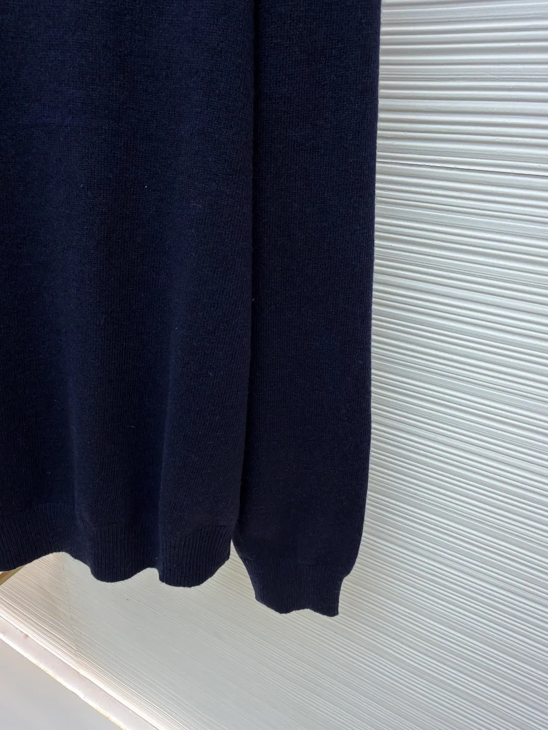 Burberry embroidered half-zip turtleneck sweater ●Original version: Purchased and developed by 4472 ●Item number: 1681783-B25 ●Material: wool blended fabric ●Technology: knitted production ●Color: navy ●Version: Fitted version ●Weight: about 545 grams ●Size: S-M-L-XL ●Description: Cashmere is used as the main body to dominate the feel, warmth and lightness of the fabric, while providing an unparalleled wearing experience. A small amount of polyamide and Lycra are added to enhance the overall durability and pilling resistance. An invisible support network is woven into the soft cashmere, and it also has a certain amount of elasticity to better fit the curves of the human body and allow it to be retracted and retracted freely. Due to the characteristics of the sweater fabric, it is stretched just right when stretching the frame, and then a hot-melt liner is used under the wool fabric piece to provide it with a certain temporary stable support to prevent it from shrinking after removal, causing pattern distortion, wrinkles and stitch dents. The high-precision calculation program system of the computer embroidery machine controls the movement of the embroidery frame in the X/Y direction, while the needle shuttles up and down, embroidering according to the set path, automatically completing thread trimming, thread jumping and other actions to form a stitch track, automatically adjusting the upper and lower thread tension to ensure that the stitches are smooth and free of floating threads, forming a war horse pattern with an error of ±0.1mm. Add detergent and preliminarily rinse the bulk goods at a water temperature of about 35 degrees to remove impurities during the production process, and then use protease to gently digest the hairiness on the surface to reduce the tendency of pilling from the root, improve the hand feel, retain softness, and eliminate irritation. After the final dehydration and drying process, the overall wiring is straight and delicate, the fabric is comfortable and soft, and the color is consistent without color difference. It can be matched with the same style to create a fashionable look and control various occasions. Customized accessories, complete with three standards, same style for men and women!