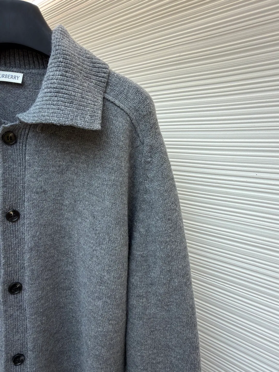 Burberry lapel rib knitted cashmere sweater ●Original version: purchased and developed by 11575 ●Item number: 1682227-B15 ●Fabric: wool blended fabric ●Technology: knitted ●Color: gray ●Version: fitted version ●Weight: about 580 grams ●Size: S-M-L-XL ●Description: This black knitted cardigan is knitted with high-count worsted wool yarn. The main body is built using four-flat stitch technology, which gives the fabric good elasticity and shapeability, while forming a fine and tight texture. The ribbed lapel weaving process is used at the neckline, and a combination of different needle types is used to create a crisp collar profile. The rib structure can be freely expanded and contracted according to the wearing status to fit the neck line. The placket adopts inlaid buttonhole technology and is matched with matte resin buttons of the same color. The buttons and the body are fixed by hand-stitching, which is strong and beautiful. The brand logo patch on the lower side of the body is processed by a hot-pressing bonding process and fits seamlessly with the knitted fabric. The overall cut is a slightly loose shoulder-drop version, combined with three-dimensional darting technology, which ensures wearing comfort while creating clean lines. Every knitting node is manually inspected to ensure the uniformity and integrity of the knitted texture. The overall wiring is straight and delicate, the fabric is comfortable and soft, and the color is consistent without color difference. It can be matched with the same style to create a fashionable look and control various occasions. Customized accessories, complete with three standards, same style for men and women!