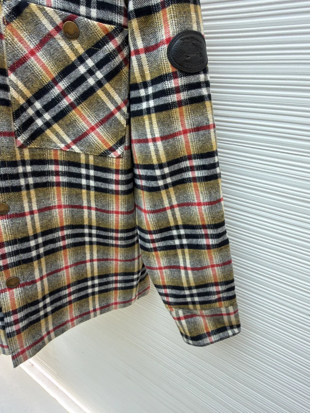 Burberry plaid wool lapel cotton coat ●Original version: Purchased and developed by 7353 ●Item number: 1681919-B40 ●Fabric: wool blended fabric ●Technology: Made on positioning cutting machine ●Color: Khaki ●Version: Fitted version ●Weight: about 800 grams ●Size: S-M-L-XL ●Description: This plaid shirt-style jacket is made of mixed-color wool blend fabric. It is combed to enhance the velvet feel and warmth, and the surface presents a natural variegated texture. The plaid pattern is based on khaki, with gray and red contrasting lines superimposed. The positioning printing process ensures that the plaid pattern is aligned when the pieces are spliced. The placket is made of vintage metal snaps, which are wear-resistant and have a thick texture; the left chest patch pocket is designed with diagonal splicing, and the bag mouth is reinforced with double-line sewing. The neckline is a classic lapel with seamed edges; the cuffs are single-button adjustable, and the inner lining is made of cotton of the same color to improve wearing comfort. The overall stitching density reaches 12 stitches/inch, and the double hemming process on the hem enhances durability. It is suitable for layering or single wear in autumn and winter. The overall wiring is straight and delicate, the fabric is comfortable and soft, and the color is consistent without color difference. It can be matched with the same style to create a fashionable look and control various occasions. Customized accessories, complete with three standards, same style for men and women!