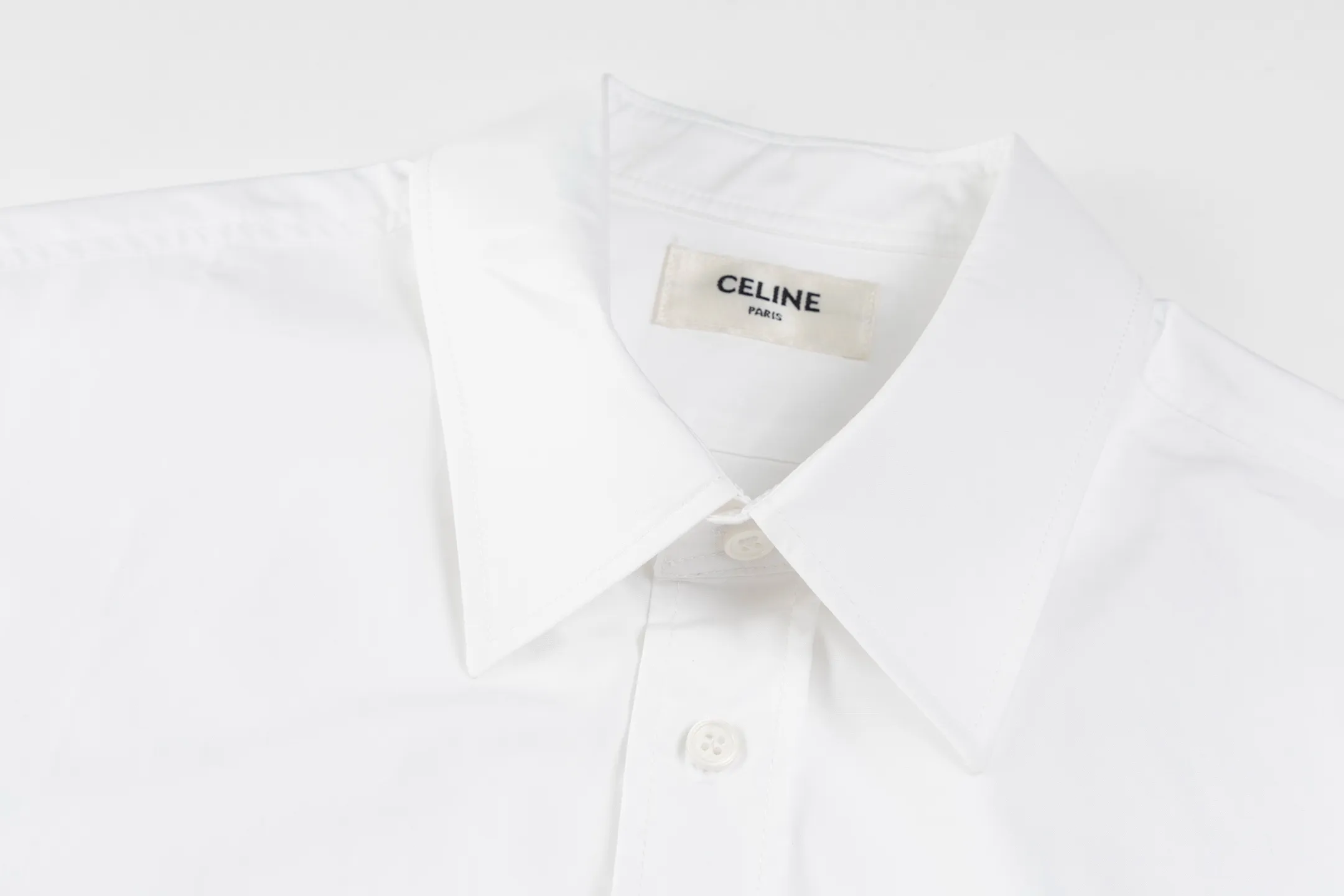 🅿️420 [Exclusive supply] Celine Arc de Triomphe small label hem long-sleeved shirt. The fabric is made of high-count cotton yarn with a high warp density and low weft density weaving process, which is light and has excellent breathability. The surface is smooth and flat, and feels as smooth as silk. At the same time, it retains the natural skin-friendly properties of cotton, making it snug and comfortable without any strange feeling. Because the warp yarns are closely arranged, the surface of the fabric shows longitudinal texture and soft luster, enhancing the visual sense of luxury. The single-color flat embroidery on the front panel uses the high-precision calculation system of the computer embroidery machine to control the coordinated operation of the machine head, needle bar, and thread spool. The fabric frame moves accurately in the horizontal and vertical directions to form a stitch track. The upper and lower thread tensions are adjusted to ensure that the stitches are smooth and free of floating threads, forming a fine pattern with an error of ±0.1mm. The ironer turns the collar up, irons it from the bottom to the top using high-temperature, moist steam, applies pressure to smooth out the wrinkles, and then turns it over to the front and repeats the process. Turn to the neckline and iron it into an arc shape, and press the back neckline to the bottom to keep it straight. The rotator cuff part uses the hanging method to avoid crushing the edges. After adjusting the fiber density through the ironer's "push, return, and pull" technology, the shirt can better fit the body curve Size: 46-48-50-52