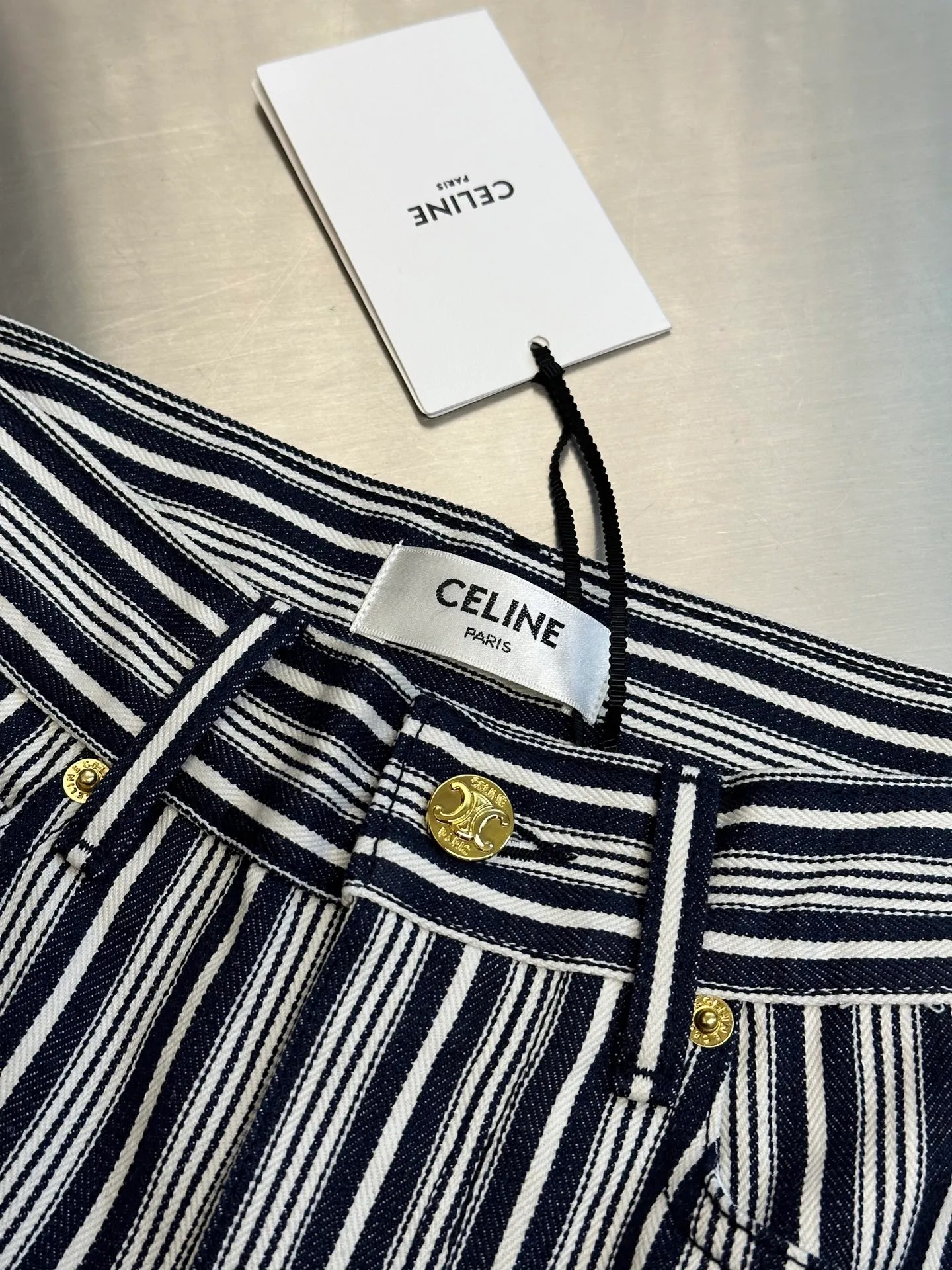 🅿️500 Celine striped straight trousers. These CELINE striped jeans cleverly combine retro elegance with modern street style. The crisp and stylish straight-leg trousers are matched with navy blue and off-white pinstripe texture, which visually makes the legs more slender. The golden metal buttons and zipper pullers on the front are engraved with the CELINE brand logo, showing exquisite style in the details.  The waistband adopts a classic five-pocket design, and the front and rear pockets are equipped with metal rivets, which combines practicality and design. The trousers are made of thick and crisp high-quality denim cotton. The fabric has a three-dimensional and clear texture. It is both durable and more textured. It is suitable for daily commuting or urban casual wear.  size：s m l