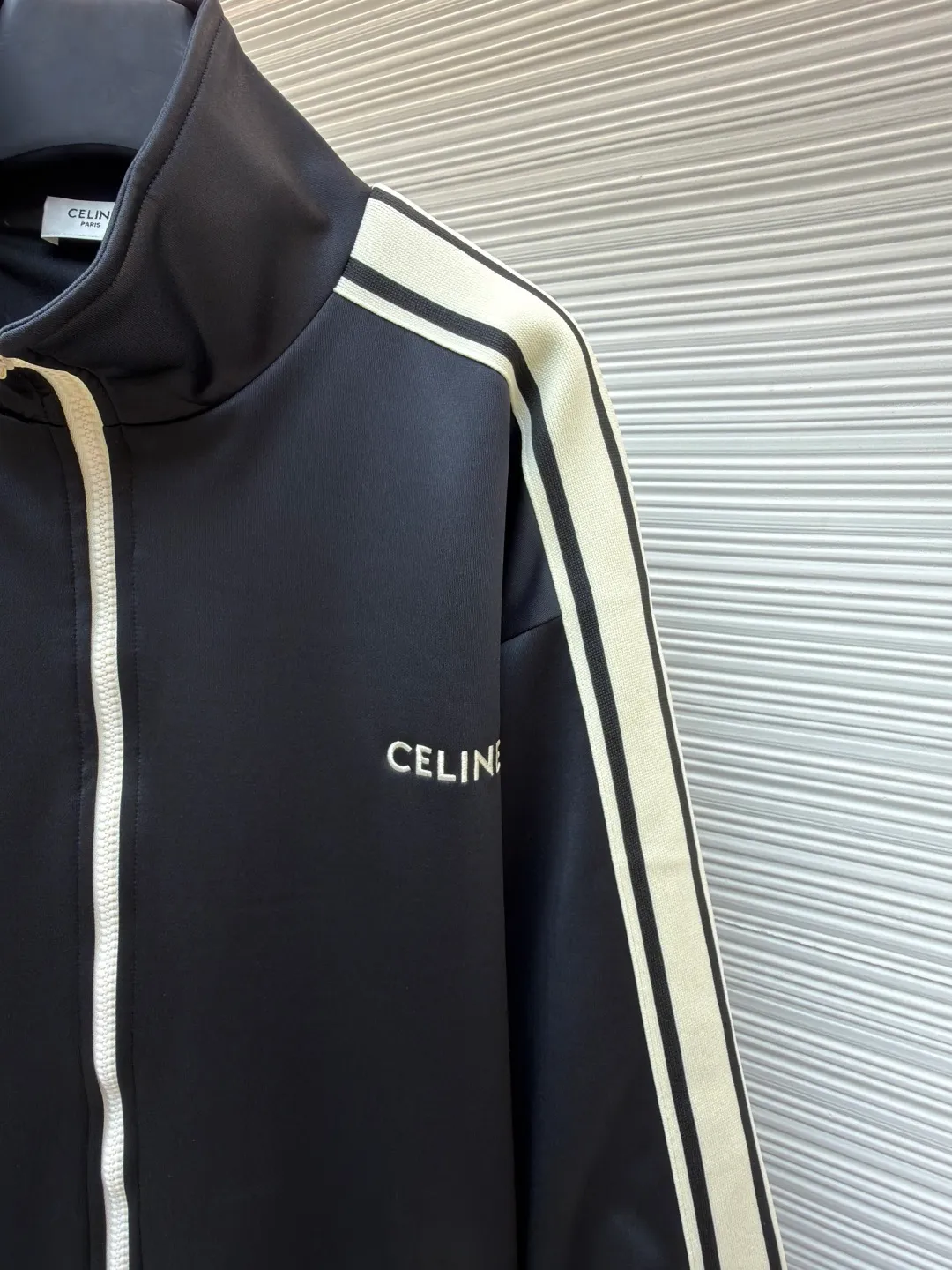 Celine side webbing splicing jacket ●Original version: Purchased and developed by 6909 ●Item number: 1681407-B70 ●Fabric: pure cotton fabric ●Technology: ribbon production ●Color: black ●Version: fitted version ●Weight: about 780 grams ●Size: XS-S-M-L ●Description: This jacket is made of high-quality smooth fabric, with a crisp texture and good drape. The stand-up collar design is equipped with a metal zipper, which is smooth and durable, and easy to open and close. The white stripes on the side of the sleeves are made of precision splicing technology, which naturally connects with the black body, and the lines are straight and smooth. The "CELINE" brand logo on the body is three-dimensional embroidery, the stitching is fine and even, and the brand is highly recognizable. The pockets on both sides are equipped with zippers, which are practical and enhance the overall texture. The rib design on the cuffs and hem has excellent elasticity and fits the body shape. From fabric selection to embroidery, splicing and zipper craftsmanship, every detail demonstrates the brand's strict control over quality, integrating sports style with high-end fashion craftsmanship, with both practicality and fashion. The overall wiring is straight and delicate, the fabric is comfortable and soft, and the color is consistent without color difference. It can be matched with the same style to create a fashionable look and control various occasions. Customized accessories, complete with three standards, same style for men and women!