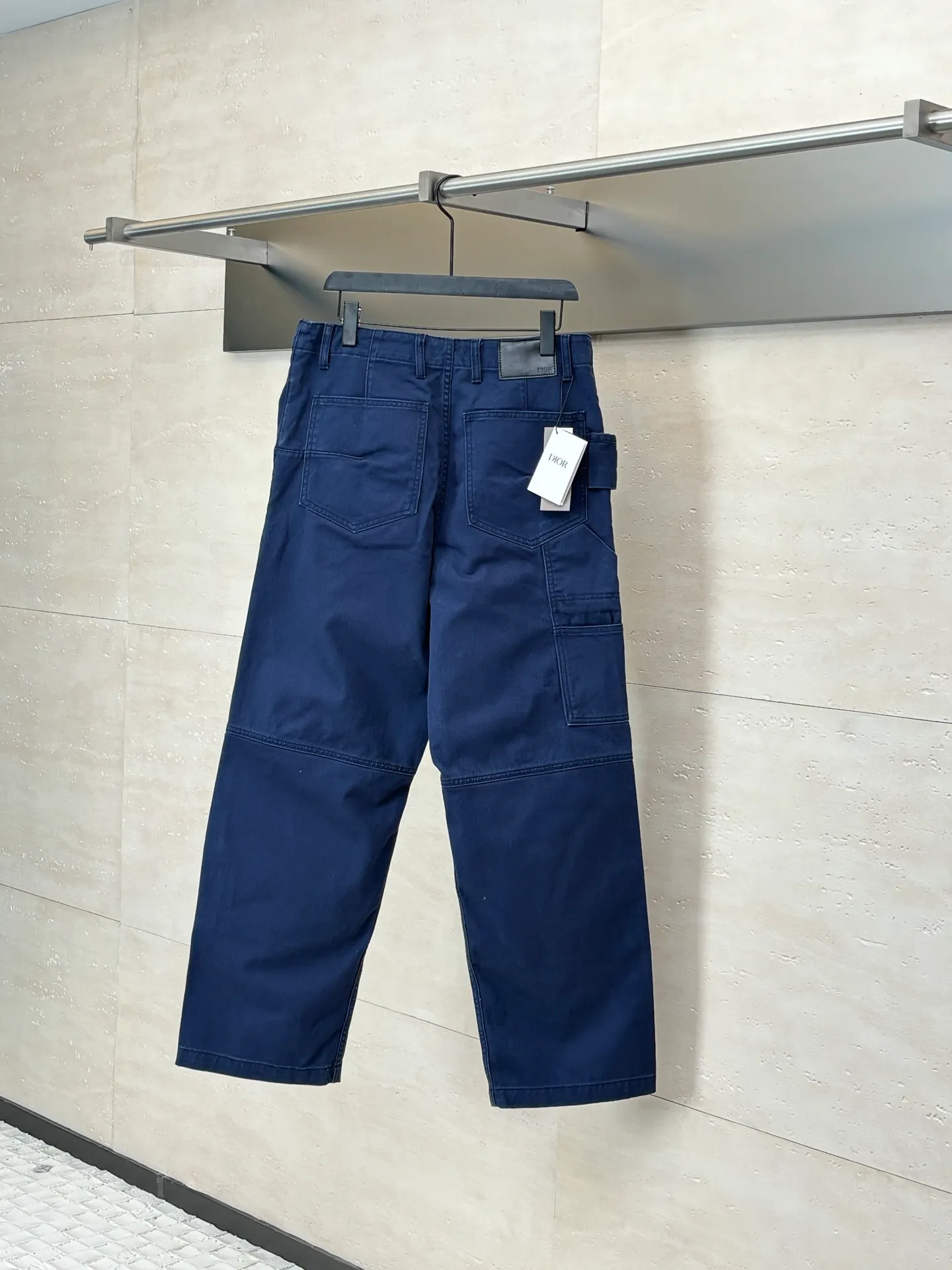 🅿️550 Dio*/Dior 25Fw new workwear blue logging French work pants. Customized twill denim (fixed dyed blue-purple) twill weaving structure. The yarn is customized using long-staple cotton + trace elastic fiber (≤3%) blend. Through the ring spinning + siro spinning composite process, the yarn has high strength and delicate surface. Pre-dyed yarn, cotton yarn is first dip-dyed with indigo 6 times (3-4 times for ordinary jeans) to ensure that the core layer is dyed through. The post-finishing uses nano-scale fixatives to give the blue a deep-sea gradient effect.   The front panel is three-dimensionally spliced, and the five-piece structure of traditional overalls is disassembled into nine asymmetrical pieces. The ergonomic curves are determined through 3D laser scanning. Double-needle differential feeding is used at the seam bone (spacing 2.5mm) to ensure no cracking during stretching.    The back leather is made of calfskin from HAAS leather factory, which is vegetable tanned and hand-rubbed to give it a matte lizard texture. Environmentally friendly dyeing uses water-based dyes, and the edge of the leather label is processed with burnt edge sealing to prevent burrs.    Size: 48/50/52