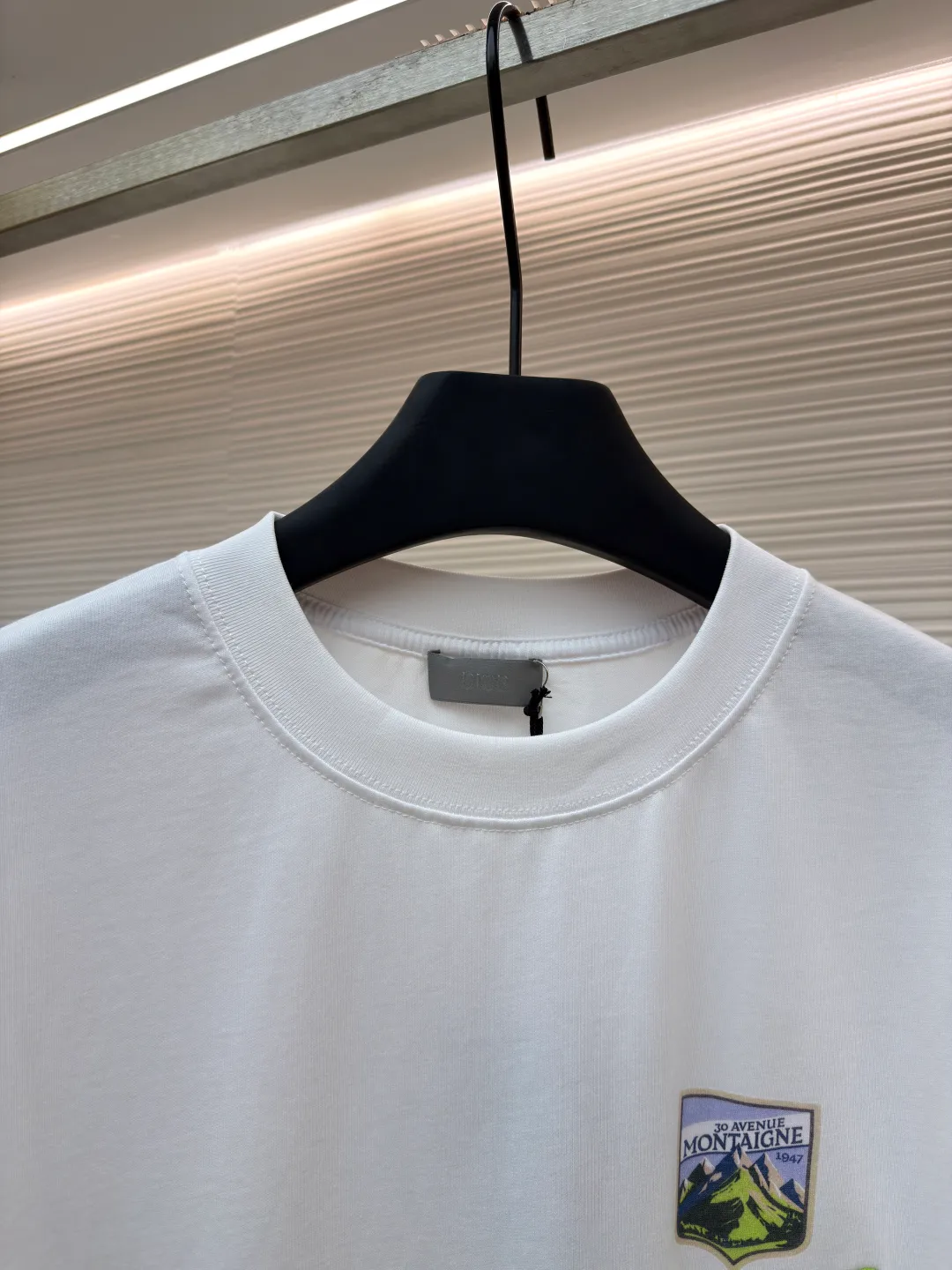 Dior Alpine Embroidery Round Neck Short Sleeve ●Original version: Purchased and developed by 7149 ●Item number: 1681102-X95 ●Fabric: plain knitted fabric ●Technology: white ink direct injection production ●Version: fitted version ●Weight: about 200 grams ●Size: S-M-L-XL ●Description: The main body is made of 24S special woven compact cotton to make plain knitted fabric, weight 180g. High-count combed cotton yarn eliminates most of the short hairiness through compact spinning process, making the yarn smoother and stronger. The woven fabric structure is extremely dense, flat and soft, with excellent anti-pilling ability and durability, while retaining the natural advantages of pure cotton, which is breathable and skin-friendly. The neckline is made of 32S 1x1 rib with a weight of 300g. The finer yarn count creates a more delicate and tight thread, which provides better elasticity and deformation resistance than ordinary ribs, ensuring that the neckline can still remain stiff after being put on and taken off many times. The printed pattern and classic logo inspired by the mountain spirit on the chest become the visual focus through the decoration combined with multiple techniques. The printed pattern elements use digital white ink direct injection technology, which presents bright, opaque white and color patterns on dark fabrics with clear edges and a smooth touch. The classic logo is completed with fluorescent green contrasting letters in the form of patches, which are then precisely sewn onto the fabric using appliqué technology. This process restores the three-dimensionality, color saturation and detail accuracy of the pattern to the original version. With the standard round neck shape and basic color, this product has established a high degree of matching tolerance. It can be mixed and matched with daily jeans or shorts, catering to the pursuit of functionality, comfort and details. The neckline has a rounded arc, suitable for various face shapes and body shapes; the sleeves are moderate and end just above the elbow, showing a smart and neat image. The slim-fitting cut shows off the wearer's body curves without sacrificing comfort. The collar, cuffs, hem and other parts are all sewn with fine double-needle stitching. The overall wiring is straight and delicate, the fabric is comfortable and soft, and the color is consistent without color difference. It can be matched with the same style to create a fashionable look and control various occasions. Customized accessories, complete with three standards, same style for men and women!