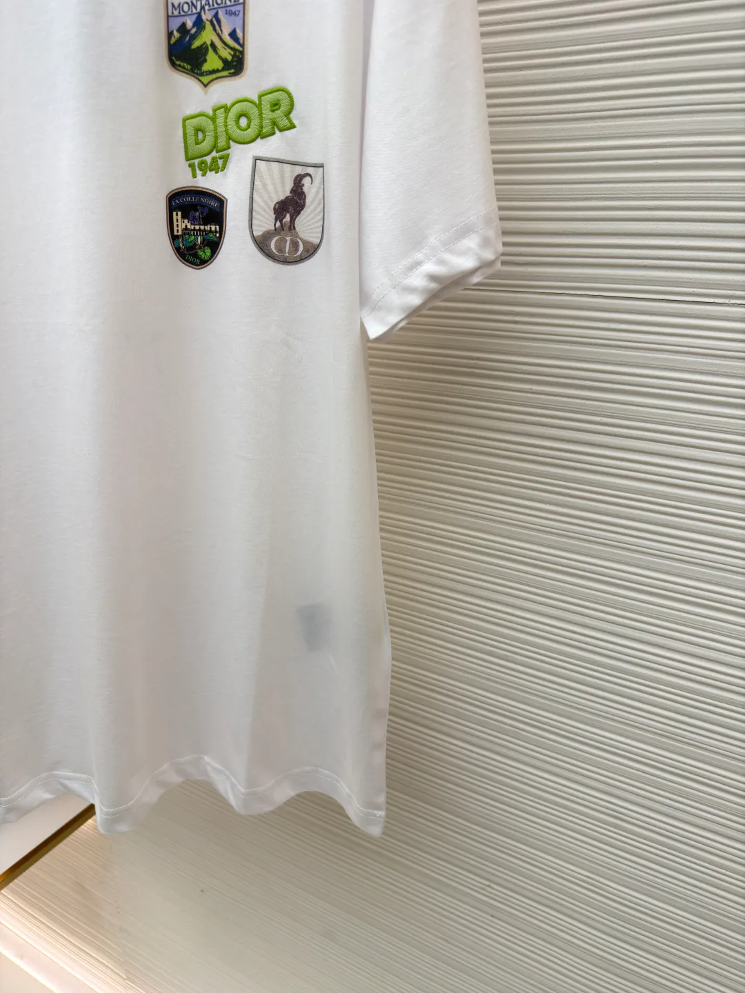 Dior Alpine Embroidery Round Neck Short Sleeve ●Original version: Purchased and developed by 7149 ●Item number: 1681102-X95 ●Fabric: plain knitted fabric ●Technology: white ink direct injection production ●Version: fitted version ●Weight: about 200 grams ●Size: S-M-L-XL ●Description: The main body is made of 24S special woven compact cotton to make plain knitted fabric, weight 180g. High-count combed cotton yarn eliminates most of the short hairiness through compact spinning process, making the yarn smoother and stronger. The woven fabric structure is extremely dense, flat and soft, with excellent anti-pilling ability and durability, while retaining the natural advantages of pure cotton, which is breathable and skin-friendly. The neckline is made of 32S 1x1 rib with a weight of 300g. The finer yarn count creates a more delicate and tight thread, which provides better elasticity and deformation resistance than ordinary ribs, ensuring that the neckline can still remain stiff after being put on and taken off many times. The printed pattern and classic logo inspired by the mountain spirit on the chest become the visual focus through the decoration combined with multiple techniques. The printed pattern elements use digital white ink direct injection technology, which presents bright, opaque white and color patterns on dark fabrics with clear edges and a smooth touch. The classic logo is completed with fluorescent green contrasting letters in the form of patches, which are then precisely sewn onto the fabric using appliqué technology. This process restores the three-dimensionality, color saturation and detail accuracy of the pattern to the original version. With the standard round neck shape and basic color, this product has established a high degree of matching tolerance. It can be mixed and matched with daily jeans or shorts, catering to the pursuit of functionality, comfort and details. The neckline has a rounded arc, suitable for various face shapes and body shapes; the sleeves are moderate and end just above the elbow, showing a smart and neat image. The slim-fitting cut shows off the wearer's body curves without sacrificing comfort. The collar, cuffs, hem and other parts are all sewn with fine double-needle stitching. The overall wiring is straight and delicate, the fabric is comfortable and soft, and the color is consistent without color difference. It can be matched with the same style to create a fashionable look and control various occasions. Customized accessories, complete with three standards, same style for men and women!