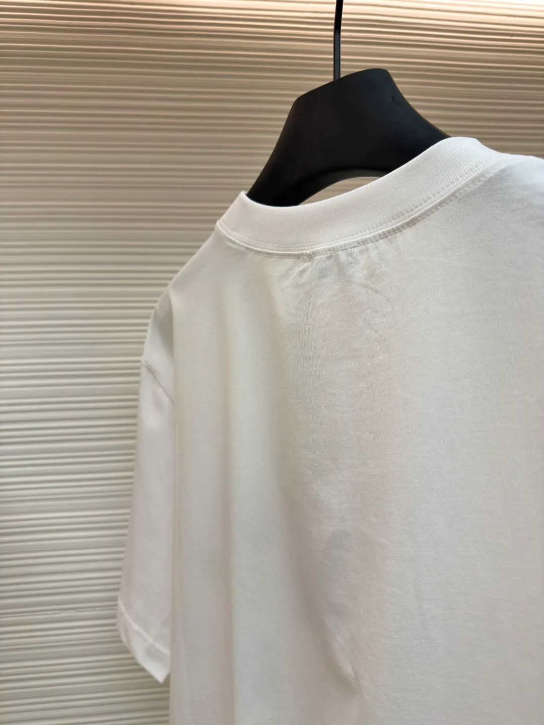 Dior Alpine Embroidery Round Neck Short Sleeve ●Original version: Purchased and developed by 7149 ●Item number: 1681102-X95 ●Fabric: plain knitted fabric ●Technology: white ink direct injection production ●Version: fitted version ●Weight: about 200 grams ●Size: S-M-L-XL ●Description: The main body is made of 24S special woven compact cotton to make plain knitted fabric, weight 180g. High-count combed cotton yarn eliminates most of the short hairiness through compact spinning process, making the yarn smoother and stronger. The woven fabric structure is extremely dense, flat and soft, with excellent anti-pilling ability and durability, while retaining the natural advantages of pure cotton, which is breathable and skin-friendly. The neckline is made of 32S 1x1 rib with a weight of 300g. The finer yarn count creates a more delicate and tight thread, which provides better elasticity and deformation resistance than ordinary ribs, ensuring that the neckline can still remain stiff after being put on and taken off many times. The printed pattern and classic logo inspired by the mountain spirit on the chest become the visual focus through the decoration combined with multiple techniques. The printed pattern elements use digital white ink direct injection technology, which presents bright, opaque white and color patterns on dark fabrics with clear edges and a smooth touch. The classic logo is completed with fluorescent green contrasting letters in the form of patches, which are then precisely sewn onto the fabric using appliqué technology. This process restores the three-dimensionality, color saturation and detail accuracy of the pattern to the original version. With the standard round neck shape and basic color, this product has established a high degree of matching tolerance. It can be mixed and matched with daily jeans or shorts, catering to the pursuit of functionality, comfort and details. The neckline has a rounded arc, suitable for various face shapes and body shapes; the sleeves are moderate and end just above the elbow, showing a smart and neat image. The slim-fitting cut shows off the wearer's body curves without sacrificing comfort. The collar, cuffs, hem and other parts are all sewn with fine double-needle stitching. The overall wiring is straight and delicate, the fabric is comfortable and soft, and the color is consistent without color difference. It can be matched with the same style to create a fashionable look and control various occasions. Customized accessories, complete with three standards, same style for men and women!