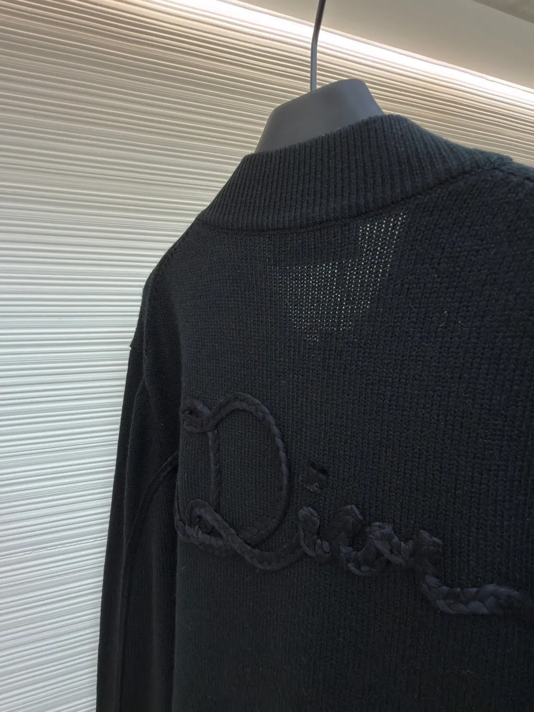 Dior letter embroidered wool knitted cardigan ●Original version: Purchased and developed by 18684 ●Item number: 1682138-C05 ●Fabric: wool blended fabric ●Technology: knitting ●Color: black ●Version: fitted version ●Weight: about 755 grams ●Size: S-M-L-XL ●Description: This Dior black knitted zipper cardigan is made of high-count worsted wool and mulberry silk blended yarn. It is woven with plain knitting technology on an Italian 16-needle computerized flat machine. The yarn is first treated with anti-pilling and pre-shrunk to make the garment soft and resistant to deformation. The Dior logo on the front chest adopts dark embroidery technology, using matte embroidery thread of the same color, completed with 0.1mm fine stitching, which is low-key and rich in texture; the three-dimensional Dior letters on the back use hand-made rope embroidery techniques, and the woven rope straps are fixed segment by section according to the outline of the version, forming a 3D relief effect. The connection between the rope strap and the body adopts invisible locking technology, without any abrupt threads. The inner side of the collar is spliced ​​with breathable mesh fabric, the metal zipper is made of custom matte nickel material, and the teeth are treated with wear-resistant treatment. The ribbed edges of the cuffs and hem have built-in elastic spandex yarn, and are hand-ironed and shaped. Every craftsmanship detail is in line with Dior's high-end ready-to-wear production standards. The overall wiring is straight and delicate, the fabric is comfortable and soft, and the color is consistent without color difference. It can be matched with the same style to create a fashionable look and control various occasions. Customized accessories, complete with three standards, same style for men and women!
