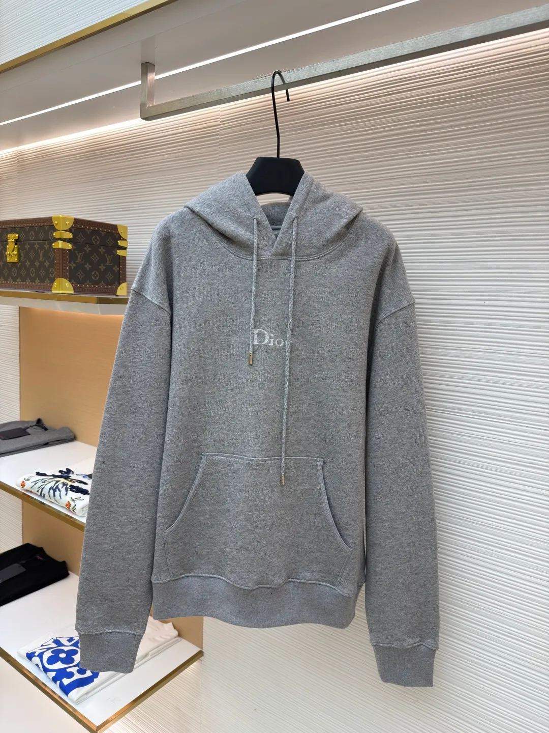 Dior classic logo embroidered hooded sweatshirt ●Item number: 1682332-A75 ●Material: cotton fabric ●Technology: embroidery production ●Color: gray ●Version: fitted version ●Weight: about 645 grams ●Size: XS-S-M-L ●Description: It adopts a fleece fabric structure of 26 counts of double yarn + 10S plush bottom, with a weight of 380g/㎡, and 21 counts of 1x1 ribs with a weight of 470g/㎡. It is used for the cuffs and hem. Its extremely high weight ensures the ultimate thickness, stiffness and deformation resistance of these closing parts, forming a unified and strong outline with the body. The fabric is a heavyweight and high-quality sweatshirt fabric. The 26-count double yarn forms a smooth, delicate and strong outer surface of the fabric, ensuring good color fastness and appearance. The 10S plush base undergoes a precise fleece or brushing process to form a layer of rich, dense and uniform fluff on the inside of the fabric. This makes the sweatshirt have a crisp and skeletal feel on the outside and an extremely soft and warm feel on the inside. White tone twill needle embroidery process. Needle embroidery is a straight line embroidery with stitches closely connected and evenly arranged. It is often used to outline clear and sharp outlines. This stitch is used to embroider a diagonal stripe pattern with a certain angle and width. Use white embroidery thread to follow the preset diagonal trajectory and perform precise embroidery with high-density stitches. On the high-weight fabric base, simple, exquisite and three-dimensional line decoration is created. The contrast between white and fabric color is sharp, and the slightly convex texture brought by the embroidery adds a visual and tactile layer, effectively enhancing the exquisite style of the basic sweatshirt. The overall wiring is straight and delicate, the fabric is comfortable and soft, and the color is consistent without color difference. It can be matched with the same style to create a fashionable look and control various occasions. Customized accessories, complete with three standards, same style for men and women!