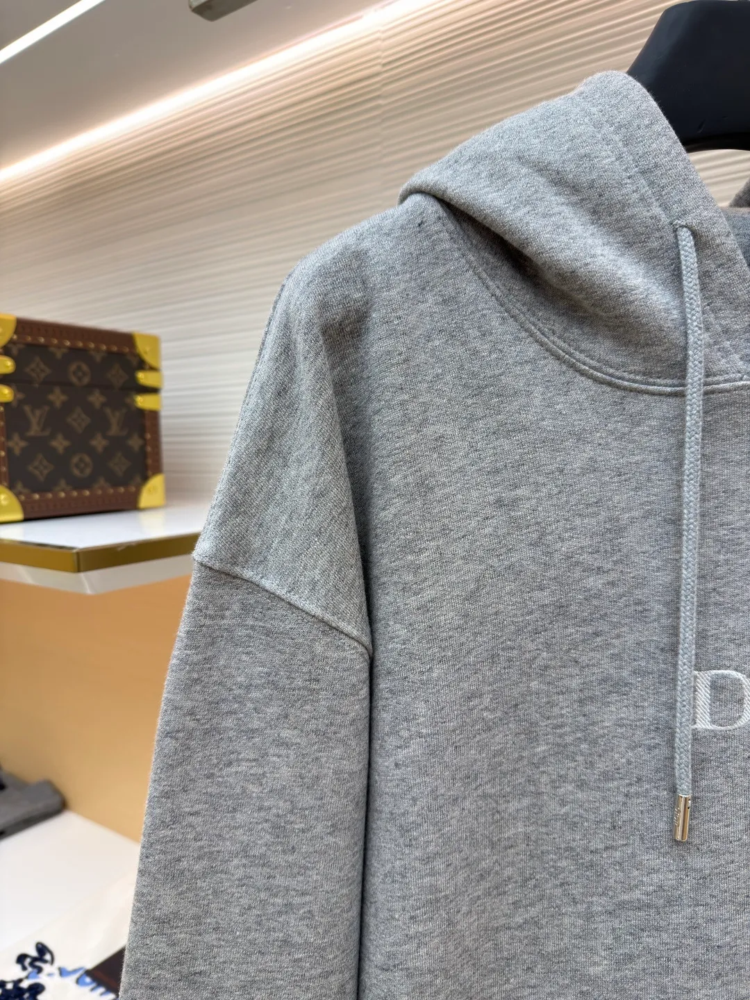 Dior classic logo embroidered hooded sweatshirt ●Item number: 1682332-A75 ●Material: cotton fabric ●Technology: embroidery production ●Color: gray ●Version: fitted version ●Weight: about 645 grams ●Size: XS-S-M-L ●Description: It adopts a fleece fabric structure of 26 counts of double yarn + 10S plush bottom, with a weight of 380g/㎡, and 21 counts of 1x1 ribs with a weight of 470g/㎡. It is used for the cuffs and hem. Its extremely high weight ensures the ultimate thickness, stiffness and deformation resistance of these closing parts, forming a unified and strong outline with the body. The fabric is a heavyweight and high-quality sweatshirt fabric. The 26-count double yarn forms a smooth, delicate and strong outer surface of the fabric, ensuring good color fastness and appearance. The 10S plush base undergoes a precise fleece or brushing process to form a layer of rich, dense and uniform fluff on the inside of the fabric. This makes the sweatshirt have a crisp and skeletal feel on the outside and an extremely soft and warm feel on the inside. White tone twill needle embroidery process. Needle embroidery is a straight line embroidery with stitches closely connected and evenly arranged. It is often used to outline clear and sharp outlines. This stitch is used to embroider a diagonal stripe pattern with a certain angle and width. Use white embroidery thread to follow the preset diagonal trajectory and perform precise embroidery with high-density stitches. On the high-weight fabric base, simple, exquisite and three-dimensional line decoration is created. The contrast between white and fabric color is sharp, and the slightly convex texture brought by the embroidery adds a visual and tactile layer, effectively enhancing the exquisite style of the basic sweatshirt. The overall wiring is straight and delicate, the fabric is comfortable and soft, and the color is consistent without color difference. It can be matched with the same style to create a fashionable look and control various occasions. Customized accessories, complete with three standards, same style for men and women!