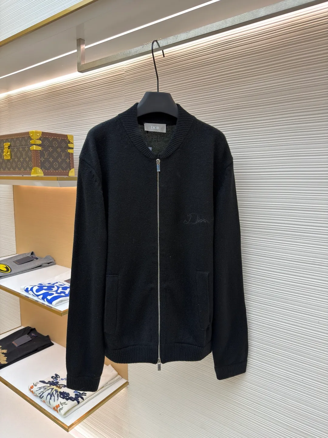 Dior letter embroidered wool knitted cardigan ●Original version: Purchased and developed by 18684 ●Item number: 1682138-C05 ●Fabric: wool blended fabric ●Technology: knitting ●Color: black ●Version: fitted version ●Weight: about 755 grams ●Size: S-M-L-XL ●Description: This Dior black knitted zipper cardigan is made of high-count worsted wool and mulberry silk blended yarn. It is woven with plain knitting technology on an Italian 16-needle computerized flat machine. The yarn is first treated with anti-pilling and pre-shrunk to make the garment soft and resistant to deformation. The Dior logo on the front chest adopts dark embroidery technology, using matte embroidery thread of the same color, completed with 0.1mm fine stitching, which is low-key and rich in texture; the three-dimensional Dior letters on the back use hand-made rope embroidery techniques, and the woven rope straps are fixed segment by section according to the outline of the version, forming a 3D relief effect. The connection between the rope strap and the body adopts invisible locking technology, without any abrupt threads. The inner side of the collar is spliced ​​with breathable mesh fabric, the metal zipper is made of custom matte nickel material, and the teeth are treated with wear-resistant treatment. The ribbed edges of the cuffs and hem have built-in elastic spandex yarn, and are hand-ironed and shaped. Every craftsmanship detail is in line with Dior's high-end ready-to-wear production standards. The overall wiring is straight and delicate, the fabric is comfortable and soft, and the color is consistent without color difference. It can be matched with the same style to create a fashionable look and control various occasions. Customized accessories, complete with three standards, same style for men and women!