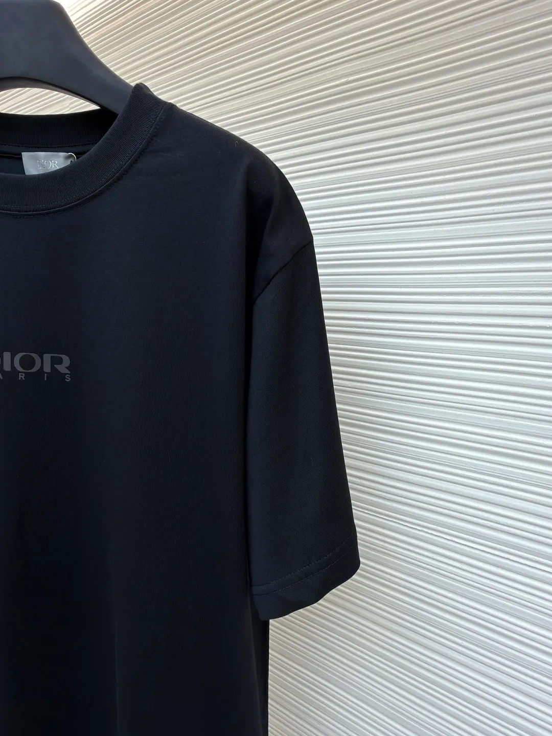 Dior Reflective Triangle Icon Round Neck Short Sleeve ●Original version: Purchased and developed by 6323 ●Item No.: 1681099-A00 ●Fabric: Jersey fabric ●Technology: Reflective lettering and embossed production ●Version: Fitted version ●Weight: about 220 grams ●Size: S-M-L-XL ●Description: The main body is made of 24S special woven compact cotton to make jersey fabric, weight 180g. High-count combed cotton yarn eliminates most of the short hairiness through compact spinning process, making the yarn smoother and stronger. The woven fabric structure is extremely dense, flat and soft, with excellent anti-pilling ability and durability, while retaining the natural advantages of pure cotton, which is breathable and skin-friendly. The neckline is made of 32S 1x1 rib with a weight of 300g. The finer yarn count creates a more delicate and tight thread, which provides better elasticity and deformation resistance than ordinary ribs, ensuring that the neckline can still remain stiff after being put on and taken off many times. The reflective engraving and embossing process is a sophisticated technology that combines safety functions with visual aesthetics. The core is to use a reflective lettering film with a built-in micro-glass bead layer. First, a high-precision laser cutting machine is used to engrave the outline according to the designed fonts and patterns to ensure that the edges are clear and burr-free. The cut reflective film is accurately attached to the surface of the fabric through heat transfer printing equipment under specific temperature and pressure, so that it is firmly combined with the fabric fibers. The case is matte silver-gray under normal conditions, but when illuminated by light, the micro-glass bead layer can achieve efficient retroreflection and instantly present a striking bright effect. The finished product is washable and abrasion resistant, perfectly meeting the dual needs of sportswear for functionality and visual tension. The overall wiring is straight and delicate, the fabric is comfortable and soft, and the color is consistent without color difference. It can be matched with the same style to create a fashionable look and control various occasions. Customized accessories, complete with three standards, same style for men and women!