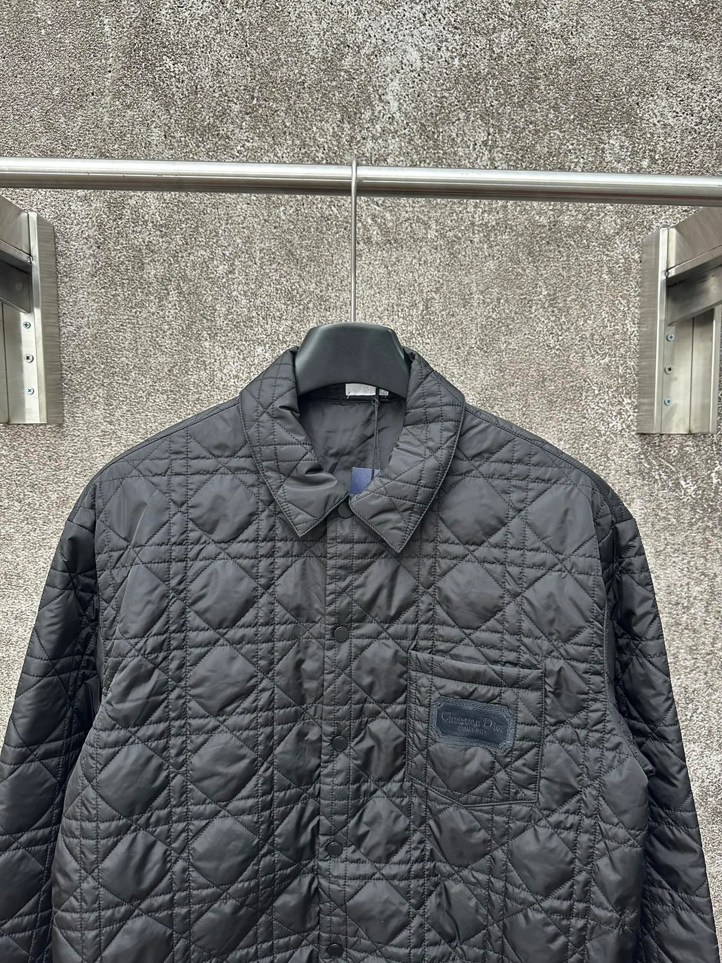 🅿️550 Dior 25ss new jacket shirt reinterprets the classic design and highlights modern style. Crafted from black technical fabric for a sleek silhouette, it's finished with a classic tonal quilted cannage pattern throughout. The chest patch pocket is decorated with +Christian+Dior+Couture+ embroidery, and the side slits are designed with snap buttons and can be worn open or buttoned. Blending traditional and modern styles, pair it with jeans or shorts for a sophisticated, stylish look.  Size: S M L XL