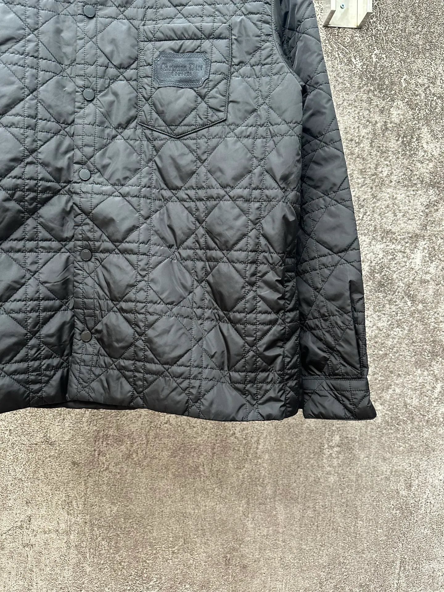 🅿️550 Dior 25ss new jacket shirt reinterprets the classic design and highlights modern style. Crafted from black technical fabric for a sleek silhouette, it's finished with a classic tonal quilted cannage pattern throughout. The chest patch pocket is decorated with +Christian+Dior+Couture+ embroidery, and the side slits are designed with snap buttons and can be worn open or buttoned. Blending traditional and modern styles, pair it with jeans or shorts for a sophisticated, stylish look.  Size: S M L XL