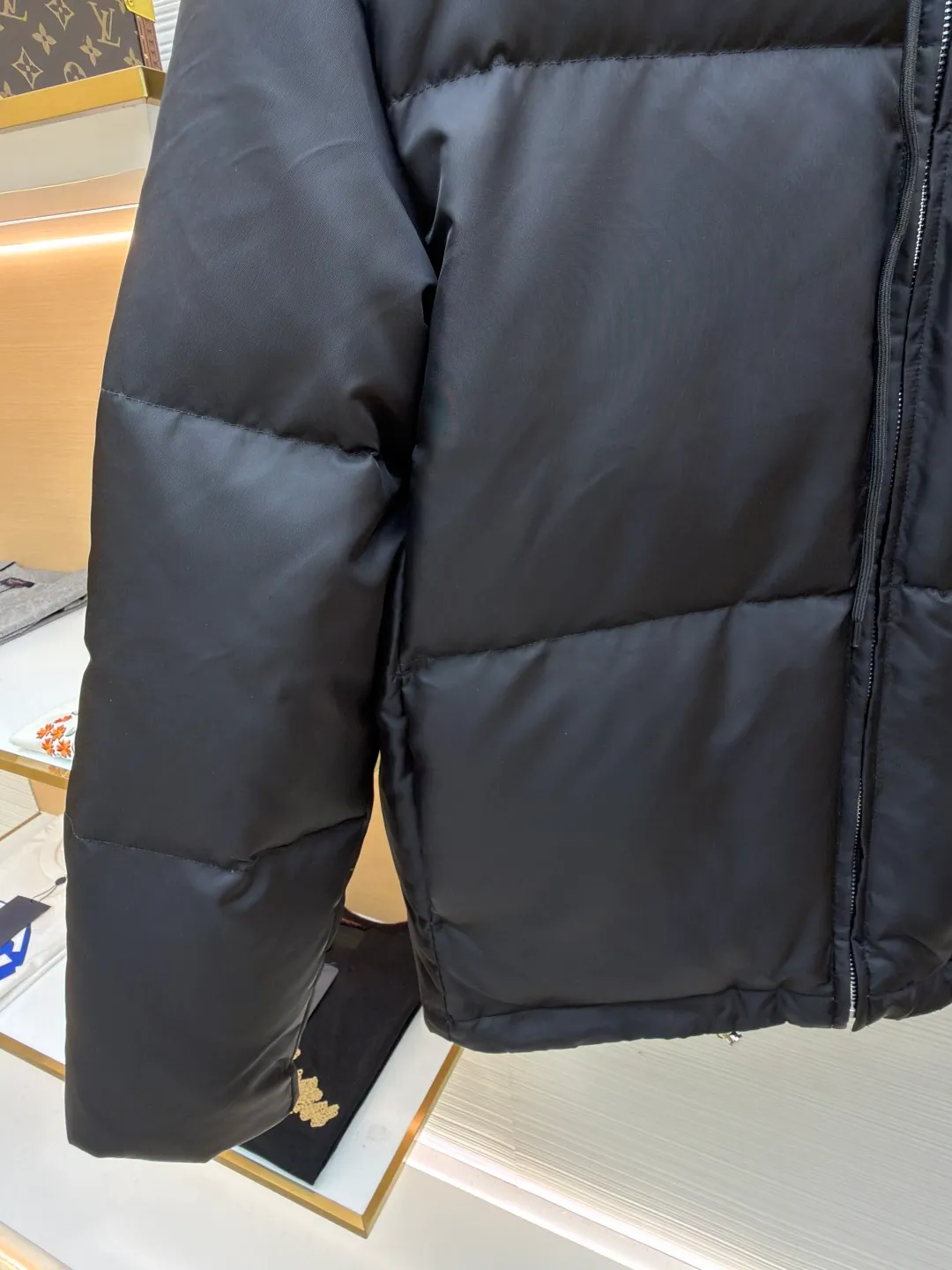 Prada Triangle Down Jacket ●Item No.: 1681316-C75 ●Fabric: White duck down fabric ●Technology: Mechanically filled with down ●Color: Black ●Version: Fitted version ●Weight: about 910 grams ●Size: S-M-L-XL ●Description: This down jacket is made of high-density water-repellent fabric, treated with a special coating, and has both windproof and anti-fouling properties. The hooded design is equipped with an adjustable drawstring, and the metal buckle at the end of the drawstring is customized by the brand, with fine texture and durability. The placket uses a two-way metal zipper with precise teeth, and the smoothness of the zipper has been tested for many rounds. The body of the garment is filled with high-quality goose down, which is evenly and plumply filled. The velvet is fixed through three-dimensional quilting technology to avoid velvet running while creating a layered silhouette. The brand triangle logo on the chest uses metal embossing + leather inlay technology, the edges are polished smooth, and the logo is three-dimensional and eye-catching. The pocket is a hidden zipper bag, and the zipper is the same color as the fabric, which is both practical and beautiful. The cuffs use micro-elastic edge processing to fit the wrist without restricting movement. The overall tailoring follows an oversize version, and seamless gluing technology is used at the splicing points to reduce thread exposure and improve wearing comfort and sophistication of garments. Every craftsmanship demonstrates Prada's strict standards for high-end clothing. The overall wiring is straight and delicate, the fabric is comfortable and soft, and the color is consistent without color difference. It can be matched with the same style to create a fashionable look and control various occasions. Customized accessories, complete with three standards, same style for men and women!