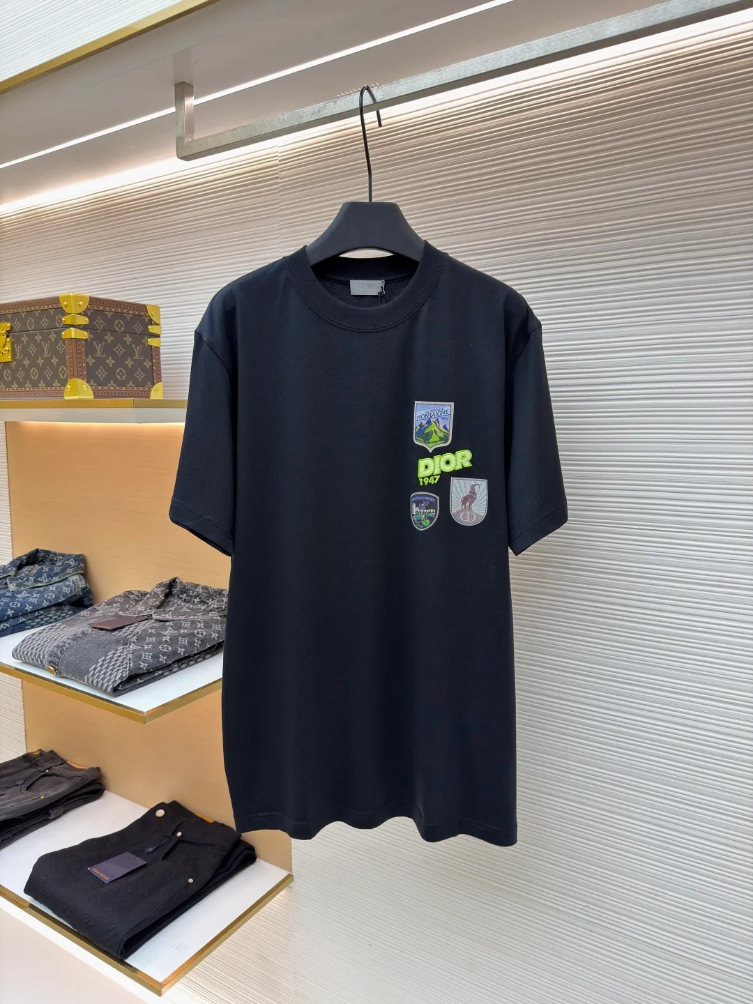 Dior Alpine Embroidery Round Neck Short Sleeve ●Original version: Purchased and developed by 7149 ●Item number: 1681101-A05 ●Fabric: plain knitted fabric ●Technology: white ink direct-injection production ●Version: fitted version ●Weight: about 215 grams ●Size: XS-S-M-L ●Description: The main body is made of 24S special woven compact cotton to make plain knitted fabric, weight 180g. High-count combed cotton yarn eliminates most of the short hairiness through compact spinning process, making the yarn smoother and stronger. The woven fabric structure is extremely dense, flat and soft, with excellent anti-pilling ability and durability, while retaining the natural advantages of pure cotton, which is breathable and skin-friendly. The neckline is made of 32S 1x1 rib with a weight of 300g. The finer yarn count creates a more delicate and tight thread, which provides better elasticity and deformation resistance than ordinary ribs, ensuring that the neckline can still remain stiff after being put on and taken off many times. The printed pattern and classic logo inspired by the mountain spirit on the chest become the visual focus through the decoration combined with multiple techniques. The printed pattern elements use digital white ink direct injection technology, which presents bright, opaque white and color patterns on dark fabrics with clear edges and a smooth touch. The classic logo is completed with fluorescent green contrasting letters in the form of patches, which are then precisely sewn onto the fabric using appliqué technology. This process restores the three-dimensionality, color saturation and detail accuracy of the pattern to the original version. With the standard round neck shape and basic color, this product has established a high degree of matching tolerance. It can be mixed and matched with daily jeans or shorts, catering to the pursuit of functionality, comfort and details. The neckline has a rounded arc, suitable for various face shapes and body shapes; the sleeves are moderate and end just above the elbow, showing a smart and neat image. The slim-fitting cut shows off the wearer's body curves without sacrificing comfort. The collar, cuffs, hem and other parts are all sewn with fine double-needle stitching. The overall wiring is straight and delicate, the fabric is comfortable and soft, and the color is consistent without color difference. It can be matched with the same style to create a fashionable look and control various occasions. Customized accessories, complete with three standards, same style for men and women!