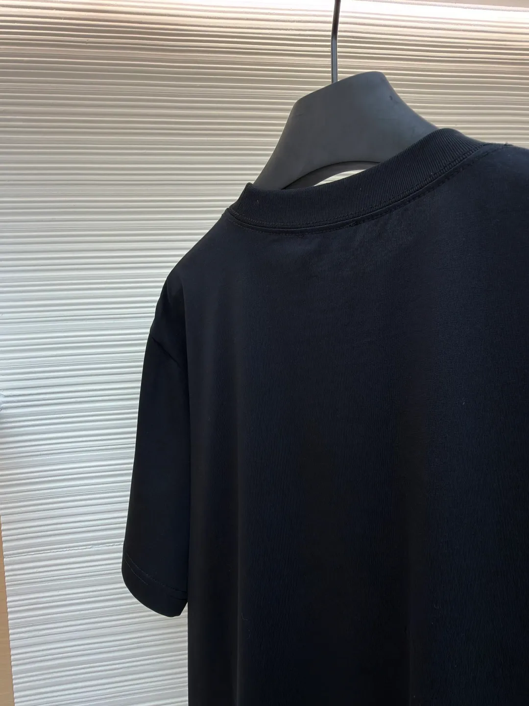 Dior Alpine Embroidery Round Neck Short Sleeve ●Original version: Purchased and developed by 7149 ●Item number: 1681101-A05 ●Fabric: plain knitted fabric ●Technology: white ink direct-injection production ●Version: fitted version ●Weight: about 215 grams ●Size: XS-S-M-L ●Description: The main body is made of 24S special woven compact cotton to make plain knitted fabric, weight 180g. High-count combed cotton yarn eliminates most of the short hairiness through compact spinning process, making the yarn smoother and stronger. The woven fabric structure is extremely dense, flat and soft, with excellent anti-pilling ability and durability, while retaining the natural advantages of pure cotton, which is breathable and skin-friendly. The neckline is made of 32S 1x1 rib with a weight of 300g. The finer yarn count creates a more delicate and tight thread, which provides better elasticity and deformation resistance than ordinary ribs, ensuring that the neckline can still remain stiff after being put on and taken off many times. The printed pattern and classic logo inspired by the mountain spirit on the chest become the visual focus through the decoration combined with multiple techniques. The printed pattern elements use digital white ink direct injection technology, which presents bright, opaque white and color patterns on dark fabrics with clear edges and a smooth touch. The classic logo is completed with fluorescent green contrasting letters in the form of patches, which are then precisely sewn onto the fabric using appliqué technology. This process restores the three-dimensionality, color saturation and detail accuracy of the pattern to the original version. With the standard round neck shape and basic color, this product has established a high degree of matching tolerance. It can be mixed and matched with daily jeans or shorts, catering to the pursuit of functionality, comfort and details. The neckline has a rounded arc, suitable for various face shapes and body shapes; the sleeves are moderate and end just above the elbow, showing a smart and neat image. The slim-fitting cut shows off the wearer's body curves without sacrificing comfort. The collar, cuffs, hem and other parts are all sewn with fine double-needle stitching. The overall wiring is straight and delicate, the fabric is comfortable and soft, and the color is consistent without color difference. It can be matched with the same style to create a fashionable look and control various occasions. Customized accessories, complete with three standards, same style for men and women!