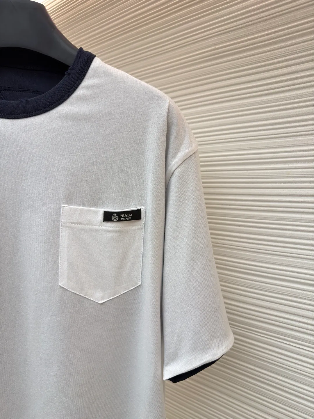 Prada double-sided design logo short sleeves ●Original version: Purchased and developed at 9150 ●Item number: 1682527-A15 ●Material: Velvet-feel plain cotton fabric ●Technology: Precision splicing and seaming production ●Color: Navy blue ●Version: Fitted version ●Weight: about 330 grams ●Size: S-M-L-XL ●Description: Customized velvet-feel plain cotton, soft and delicate, comfortable and close to the skin, twin aesthetics of gray and white interweaving Wearing the minimalist philosophy of two souls, the cloud white on the front uses Prada label details to define high-end restraint. The contrasting rib collar locks all eyes. The high-grade gray on the back uses the back triangle to highlight the essence of the brand. It is a quiet but unignorable presence. Combined with the frayed design, it is sublimated, filled with artistic atmosphere, double-sided elegance, and leads the trend. Precise splicing and seaming technology uses advanced sewing technology and equipment to ensure that the splicing of each short sleeve is smooth and tight, with smooth lines, and there will be no gaps inside and outside. The neckline is sewn using a computerized double-needle sewing process, using an advanced control system to sew two parallel stitches at the same time. Ensure that the size and shape of the neckline remain consistent, and use positioning and manual fraying. Local friction and wear on the fabric through manual operation will cause a natural damage effect on the surface of the fabric. The overall wiring is straight and delicate, the fabric is comfortable and soft, and the color is consistent without color difference. It can be matched with the same style to create a fashionable look and control various occasions. Customized accessories, complete with three standards, same style for men and women!
