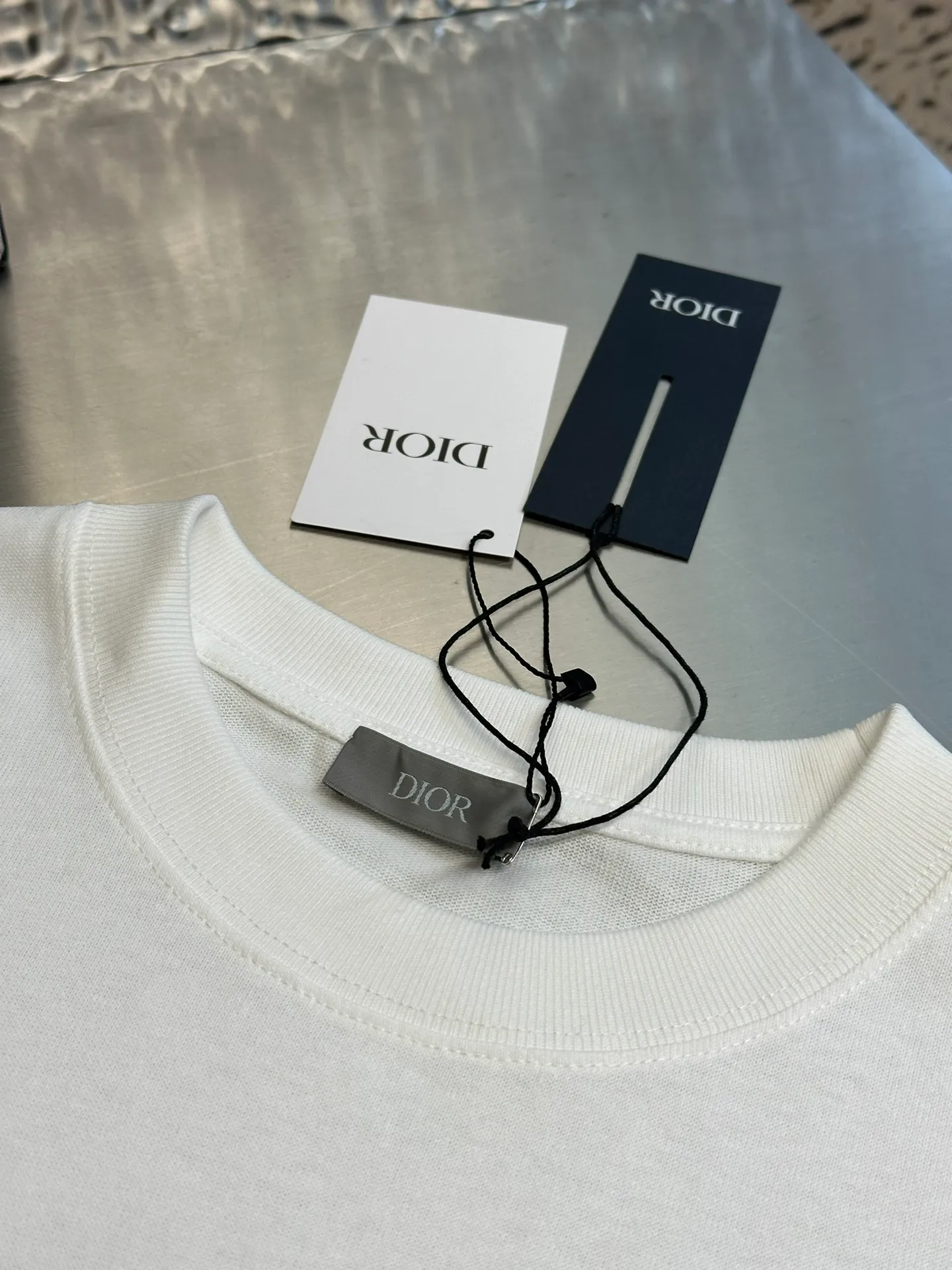 🅿️260 Dior patch letter short sleeves are made of pure cotton 12S fine cotton plain weave, weight 230g. The front is decorated with contrasting logo patches and small embroidered stamps, forming a decorative and iconic embroidery product. The logo is made of imported custom-made embroidery thread, which is dyed with lustrous mercerized embroidery thread, giving it a uniform and glossy finish. The exquisite embroidery machine combines complex embroidery needlework and fine detail processing to create a three-dimensional micro-relief embroidery effect; it is also highly durable and wear-resistant.  The standard round neck and short-sleeved version has a rounded arc neckline, which is suitable for various face shapes and body shapes; the sleeve length is moderate and ends just above the elbow, showing a smart and neat image. The slim fit can show off the wearer's body curves without sacrificing comfort. The collar, cuffs, hem and other parts are all sewn with fine double-needle stitching.  size：xs s m l