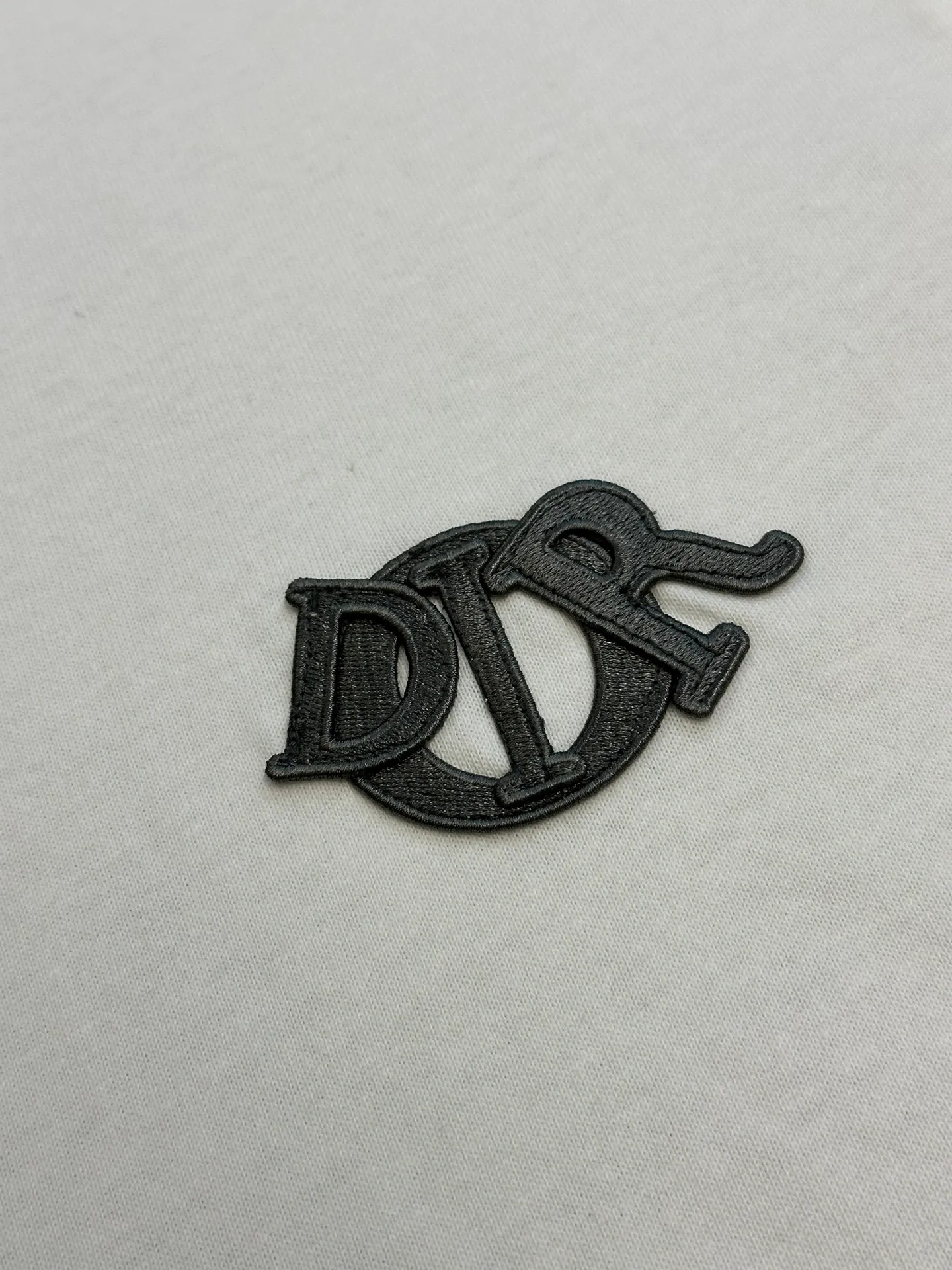 🅿️260 Dior patch letter short sleeves are made of pure cotton 12S fine cotton plain weave, weight 230g. The front is decorated with contrasting logo patches and small embroidered stamps, forming a decorative and iconic embroidery product. The logo is made of imported custom-made embroidery thread, which is dyed with lustrous mercerized embroidery thread, giving it a uniform and glossy finish. The exquisite embroidery machine combines complex embroidery needlework and fine detail processing to create a three-dimensional micro-relief embroidery effect; it is also highly durable and wear-resistant.  The standard round neck and short-sleeved version has a rounded arc neckline, which is suitable for various face shapes and body shapes; the sleeve length is moderate and ends just above the elbow, showing a smart and neat image. The slim fit can show off the wearer's body curves without sacrificing comfort. The collar, cuffs, hem and other parts are all sewn with fine double-needle stitching.  size：xs s m l