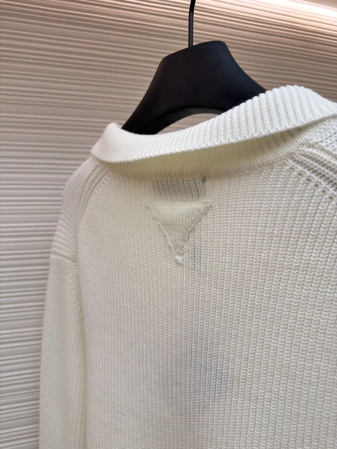 PRADA triangle logo seagull collar knitted sweater ●Item number: 1681464-A75 ●Fabric: 100% cotton ●Technology: knitted ●Color: white ●Version: Fitted version ●Weight: about 820 grams ●Size: S-M-L-XL ●Description: This sweater uses Polo collar knitting technology, with a crisp and stylish neckline, blending leisure and sophistication. Using thick needle texture weaving technology, the body texture is clear and rich in texture, creating a retro and simple style. In terms of details, the precise splicing process of the collar and placket ensures neat and natural stitching, ensuring the neatness of the silhouette; the rib knitting process of the cuffs and hem has moderate elasticity, which not only fits the body shape but also enhances the comfort of wearing. Made of high-quality knitted fabric and finely woven, it is skin-friendly, breathable and has a crisp silhouette. From the design of the neckline to the presentation of texture, every craftsmanship reflects the pursuit of classic styles and delicate workmanship. It is a knitted item that combines daily practicality with style. The overall wiring is straight and delicate, the fabric is comfortable and soft, and the color is consistent without color difference. It can be matched with the same style to create a fashionable look and control various occasions. Customized accessories, complete with three standards, same style for men and women!