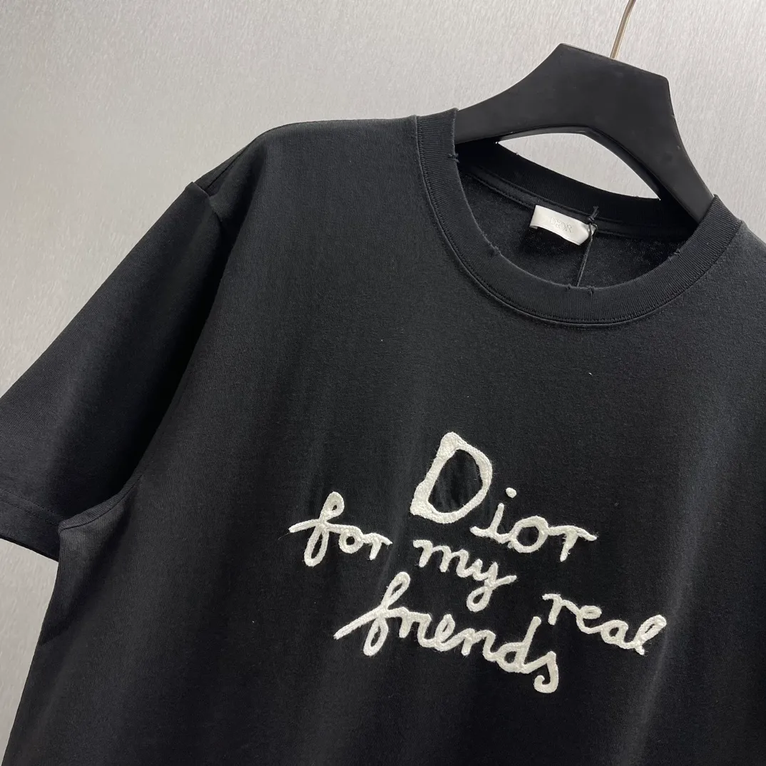 🅿️260 🧧CD True Friends Private Lettered Short Sleeves Size: S-XL This T-shirt displays the Dior For My Real Friends logo from the DIOR AND HYLTON NEL joint series. Crafted from black cotton jersey, it features a classic silhouette with a ribbed crew neck, embroidery on the chest for added style, and a burned-out effect on the collar, sleeves and hem. Cut for a relaxed fit, wear it with track pants or jeans.