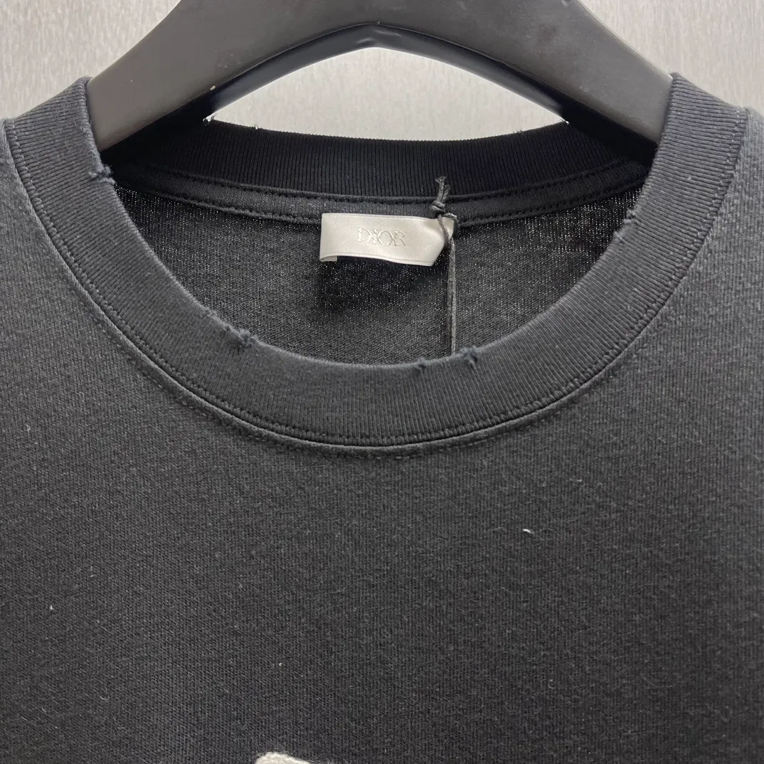 🅿️260 🧧CD True Friends Private Lettered Short Sleeves Size: S-XL This T-shirt displays the Dior For My Real Friends logo from the DIOR AND HYLTON NEL joint series. Crafted from black cotton jersey, it features a classic silhouette with a ribbed crew neck, embroidery on the chest for added style, and a burned-out effect on the collar, sleeves and hem. Cut for a relaxed fit, wear it with track pants or jeans.