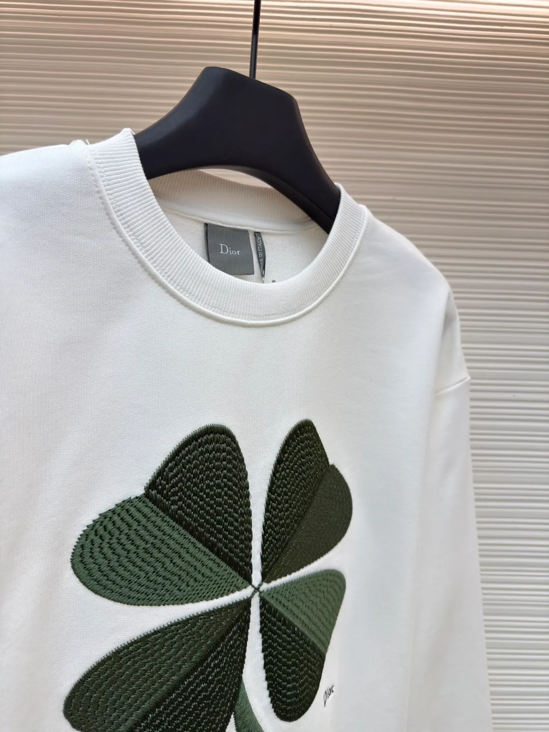 Dior four-leaf clover round neck sweatshirt ●Original version: purchased and developed by 19189 ●Item number: 1682447-A55 ●Material: pure cotton terry bottom sweatshirt fabric ●Technology: hollow embroidery production of coarse wool yarn ●Color: white ●Version: fitted version ●Weight: about 565 grams ●Size: XS-S-M-L ●Description: It adopts a fleece fabric structure of 26-count double yarn surface + 10-count yarn bottom, with a weight of 380g/㎡; with the same weight of 21-count 1x1 rib 470g/㎡. The 26-count double yarn forms a smooth and dense outer surface, and the 10-count yarn base is precisely brushed to form a rich and uniform velvet layer, thereby simultaneously achieving a crisp and skeletal feel on the outside and a skin-friendly touch like cloud velvet on the inside. Ribbing is used on the collar, cuffs and hem. Its extremely high weight and density ensure the ultimate thickness, resilience and deformation resistance of these closing parts, and together with the body, create a full and three-dimensional silhouette. The white color highlights the pure and delicate texture of the fabric and the pile loop texture on the bottom. The Dior Clover embroidery on the front uses hollow embroidery technology of coarse wool yarn. Refers to the use of special embroidery thread that is thicker and may have a plush texture. Its function is to give the embroidery pattern a unique fluffy, three-dimensional and soft touch, imitating the effect of wool weaving or tufting. This is an embroidery technique that uses specific stitches to make embroidery threads form an annular or hoop-like structure on the surface of the fabric. The embroidery thread does not adhere closely to the fabric, but forms tiny air circles, creating an extremely full, three-dimensional and elastic embroidery surface. The combination of the two creates a four-leaf clover pattern that is visually eye-catching, tactilely fluffy, and extremely handmade and artistic, forming a sharp and interesting contrast with the smooth white suede. The overall wiring is straight and delicate, the fabric is comfortable and soft, and the color is consistent without color difference. It can be matched with the same style to create a fashionable look and control various occasions. Customized accessories, complete with three standards, same style for men and women!