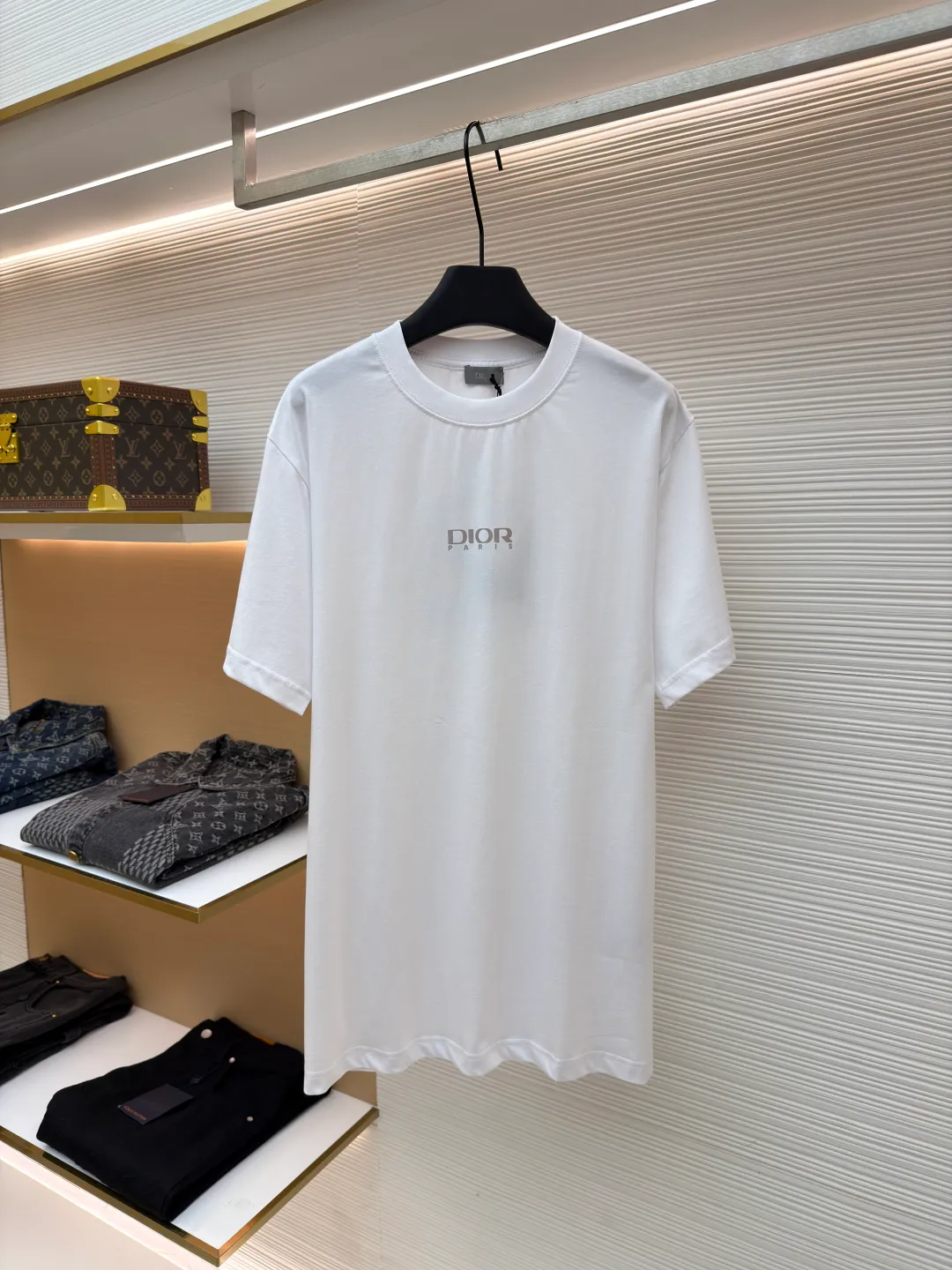 Dior Reflective Triangle Icon Round Neck Short Sleeve ●Item No.: 1681100-A00 ●Fabric: Jersey fabric ●Technology: Reflective lettering and embossed production ●Version: Fitted version ●Weight: about 205 grams ●Size: S-M-L-XL ●Description: The main body is made of 24S special woven compact cotton to make jersey fabric, weight 180g. High-count combed cotton yarn eliminates most of the short hairiness through compact spinning process, making the yarn smoother and stronger. The woven fabric structure is extremely dense, flat and soft, with excellent anti-pilling ability and durability, while retaining the natural advantages of pure cotton, which is breathable and skin-friendly. The neckline is made of 32S 1x1 rib with a weight of 300g. The finer yarn count creates a more delicate and tight thread, which provides better elasticity and deformation resistance than ordinary ribs, ensuring that the neckline can still remain stiff after being put on and taken off many times. The reflective engraving and embossing process is a sophisticated technology that combines safety functions with visual aesthetics. The core is to use a reflective lettering film with a built-in micro-glass bead layer. First, a high-precision laser cutting machine is used to engrave the outline according to the designed fonts and patterns to ensure that the edges are clear and burr-free. The cut reflective film is accurately attached to the surface of the fabric through heat transfer printing equipment under specific temperature and pressure, so that it is firmly combined with the fabric fibers. The case is matte silver-gray under normal conditions, but when illuminated by light, the micro-glass bead layer can achieve efficient retroreflection and instantly present a striking bright effect. The finished product is washable and abrasion resistant, perfectly meeting the dual needs of sportswear for functionality and visual tension. The overall wiring is straight and delicate, the fabric is comfortable and soft, and the color is consistent without color difference. It can be matched with the same style to create a fashionable look and control various occasions. Customized accessories, complete with three standards, same style for men and women!