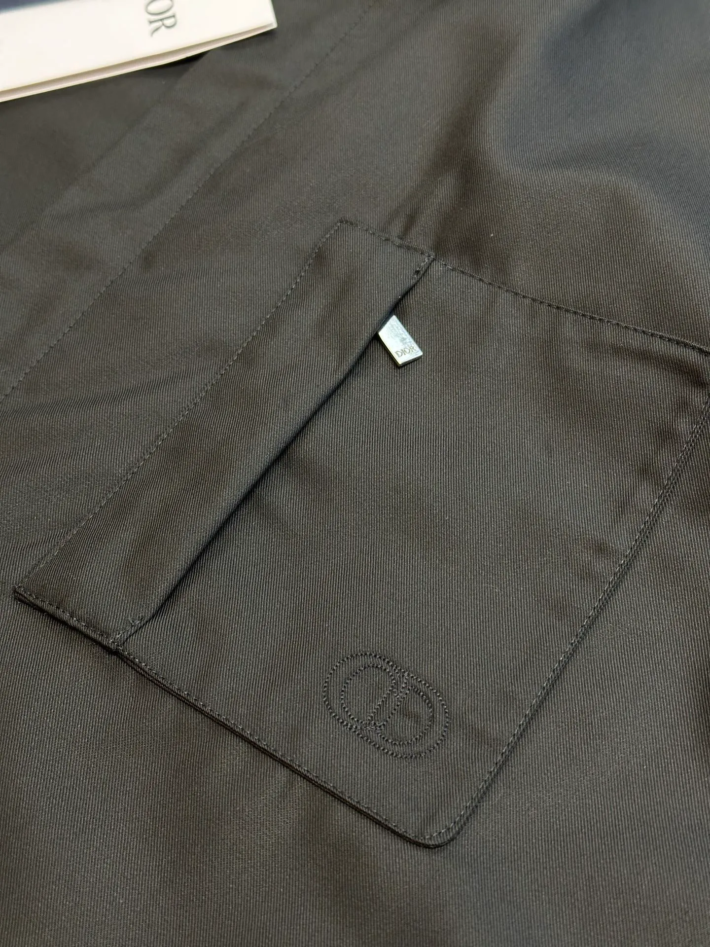 🅿️650 DIOR CD icon embroidered jacket is made of black gabardine fabric, with a smooth and delicate surface, soft touch, and elegant luster. Its tight textile construction makes it resistant to wrinkles, abrasion and drape. The wool component makes it warm and breathable. Gabardine fabric is not easy to pill, has good stain resistance, and is easy to care for daily.  The modern fit has a slim fit and a hidden zip closure adds understated sophistication. High-precision sewing technology ensures a perfect fit between the zipper and the fabric. The lapel design of traditional shirts still meets the needs of formal occasions. There is a patch pocket on the chest and is decorated with CD icon embroidery, which highlights the brand's iconic elements. The bag opening also has a hidden zipper opening, and the bag opening is reinforced with pocket knotting technology at the beginning and end. Tight stitching at the edge of the bag body makes it strong and beautiful. There are side pockets on the left and right sides, and the pocket openings are only 0.5 cm hemmed, which retains the smoothness of the overall lines without losing practicality. The double-button design of traditional shirt cuffs makes the cuffs fit more closely on the wrist and prevent them from loosening.  size：s m l xl