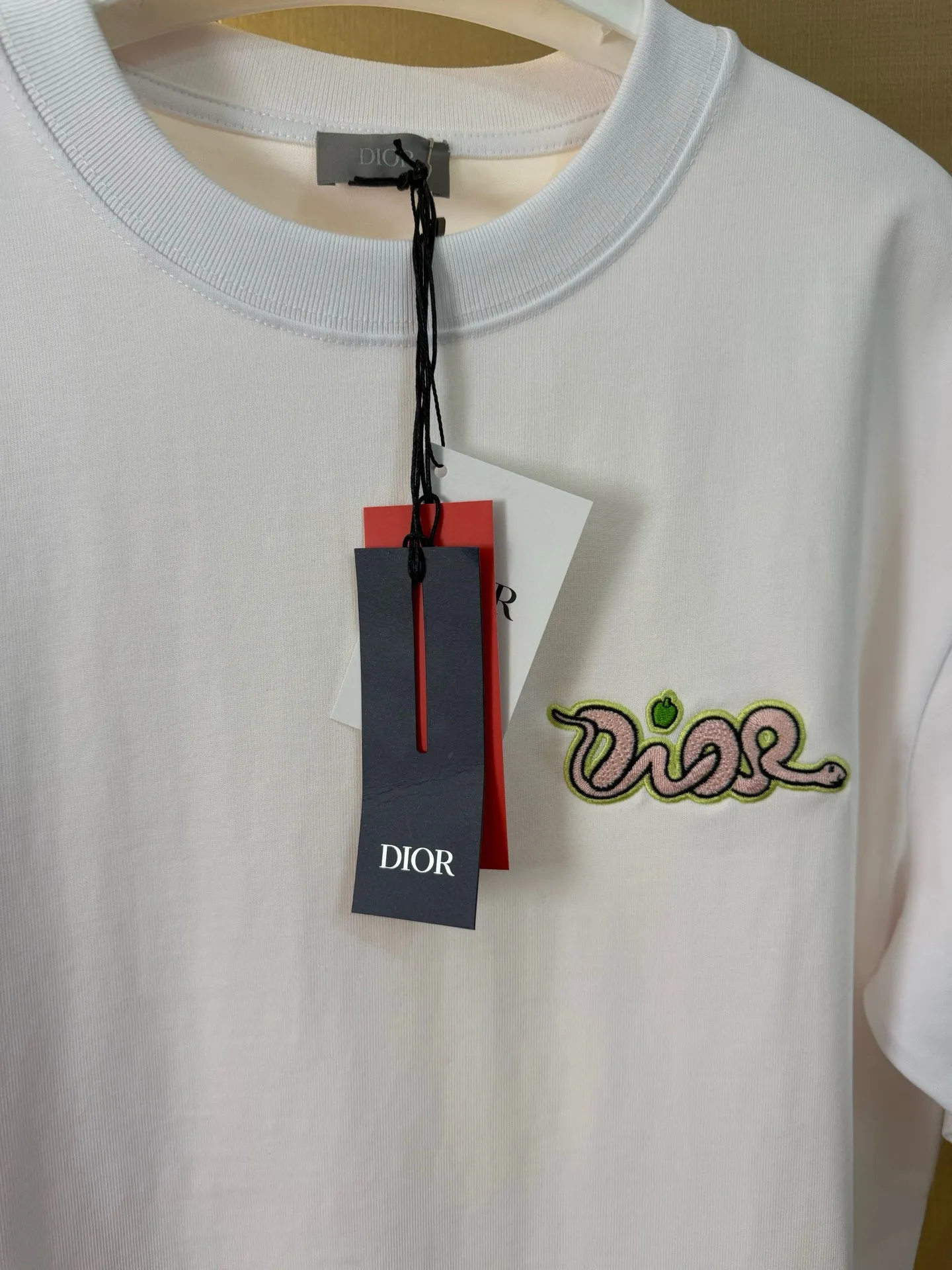 🅿️156 Dior Year of the Snake Limited Edition Apple Snake Embroidered Badge Short Sleeve Made of pure cotton 12S fine cotton plain fabric, 310g. The embroidery pattern is based on tatami embroidery technology. The embroidery uses a special single-needle arrangement. The stitches are tight and flat, forming a texture similar to the tatami grid, making the embroidery pattern have a strong three-dimensional and layered feel. Embroidered with silk threads of multiple colors, the colors are bright and contrasting, showing rich patterns and details. The outline is stroked by needle embroidery, the embroidery pattern is matched with the brand logo design, and the brand letter logo is single-needle flat embroidered. Made from a variety of needlework; the outline of the pattern is embroidered with a single straight line and straight silk thread. The outline edges and letter embroidery are stitched together to create clear and rich three-dimensional layers. The standard round neck and short-sleeved version has a rounded arc neckline, which is suitable for various face shapes and body shapes; the sleeve length is moderate and ends just above the elbow, showing a smart and neat image. The slim fit can show off the wearer's body curves without sacrificing comfort. The collar, cuffs, hem and other parts are all sewn with fine double-needle stitching. Size: S-XL