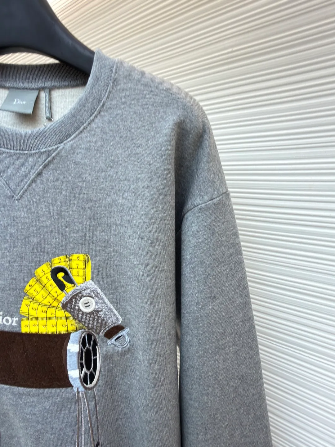 Dior horse embroidery round neck sweatshirt ●Original version: purchased and developed by 13941 ●Item number: 1682562-A70 ●Fabric: cotton fleece fabric ●Technology: embroidery production ●Color: gray ●Version: fitted version ●Weight: about 590 grams ●Size: XS-S-M-L ●Description: This product adopts a terry fabric structure of 26-count double yarn surface + 10-count yarn base, with a weight of 380g/㎡; the matching 21-count 1x1 rib also weighs 470g/㎡, and is used for the collar, cuffs and hem, and is a heavyweight sweatshirt fabric. The 26-count double yarn forms a smooth and delicate outer surface of the fabric, ensuring good color fastness. The 10-count yarn base is precision brushed to form a layer of rich, dense skin-friendly velvet on the inside of the fabric, providing excellent warmth and soft wrapping. The extremely high weight of the rib ensures the ultimate thickness, stiffness and deformation resistance of these closing parts; together with the body, it builds a full three-dimensional silhouette, and the gray color highlights the texture and high-end sense of the fabric. Environmentally friendly elastic glue printing: Printing the background of the pony pattern. This printing process is characterized by bright colors, strong coverage, and the elastic glue can stretch with the fabric without cracking, and the touch is relatively soft. Its function is to provide a large-area, flat color base and design framework for the entire pattern. Needle embroidery achieves three-dimensional reshaping of the pattern by superimposing high-density straight stitches on the printing base. It uses multi-color embroidery thread at an extreme density to continuously fill the outline and structure, accurately shaping the image and completing the color transition by changing threads. The overall wiring is straight and delicate, the fabric is comfortable and soft, and the color is consistent without color difference. It can be matched with the same style to create a fashionable look and control various occasions. Customized accessories, complete with three standards, same style for men and women!